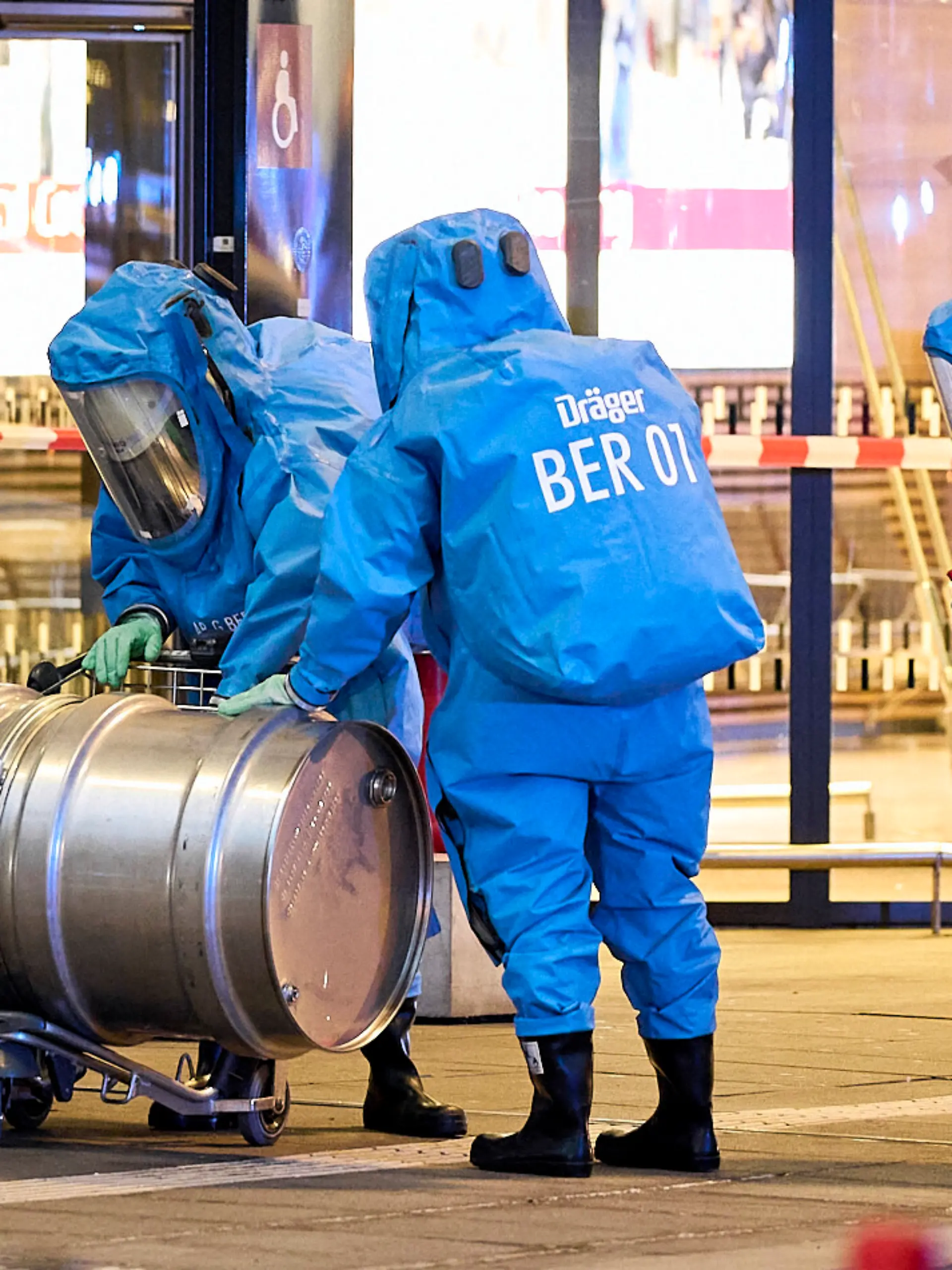 Mitglieder der Feuerwehr in Chemikalienschutzanzüge sind im Einsatz vor dem Terminal 1 am Flughafen BER. Wegen eines möglicherweise gefährlichen Stoffes ist der Terminal 1 des Hauptstadtflughafens BER am Abend teilweise geräumt worden. Die Fluggäste wurden aufgefordert, das Gebäude zu verlassen, wie ein Sprecher der Bundespolizei sagte. Demnach habe eine Frau beim Servicepoint der Bundespolizei gesagt, sie habe einen gefährlichen Stoff dabei.