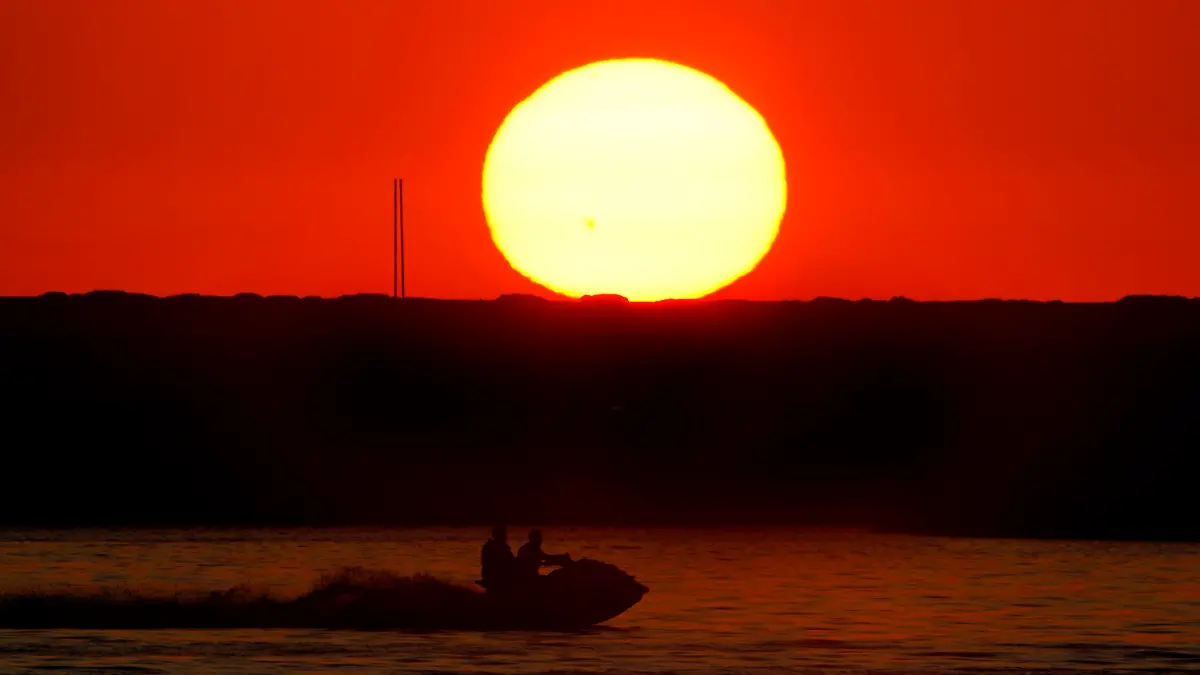 Two men ride a jet ski as the sun sets over the Mediterranean Sea coastline in Beirut, Lebanon, Wednesday, July 12, 2023. (AP Photo/Bilal Hussein)