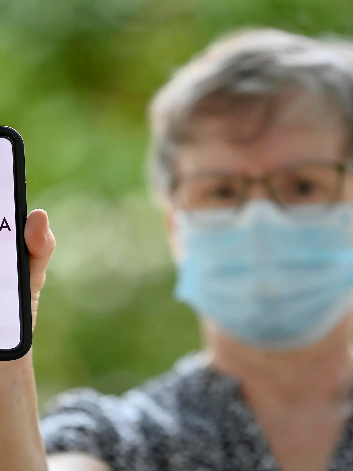  ältere Frau mit Mundschutzmaske, zeigt Smartphone mit Corona Warn-APP, Corona-Krise, Baden-Württemberg, Deutschland Coronavirus *** elderly woman with face mask, shows smartphone with Corona Warn APP, Corona crisis, Baden Württemberg, Germany Coronavirus