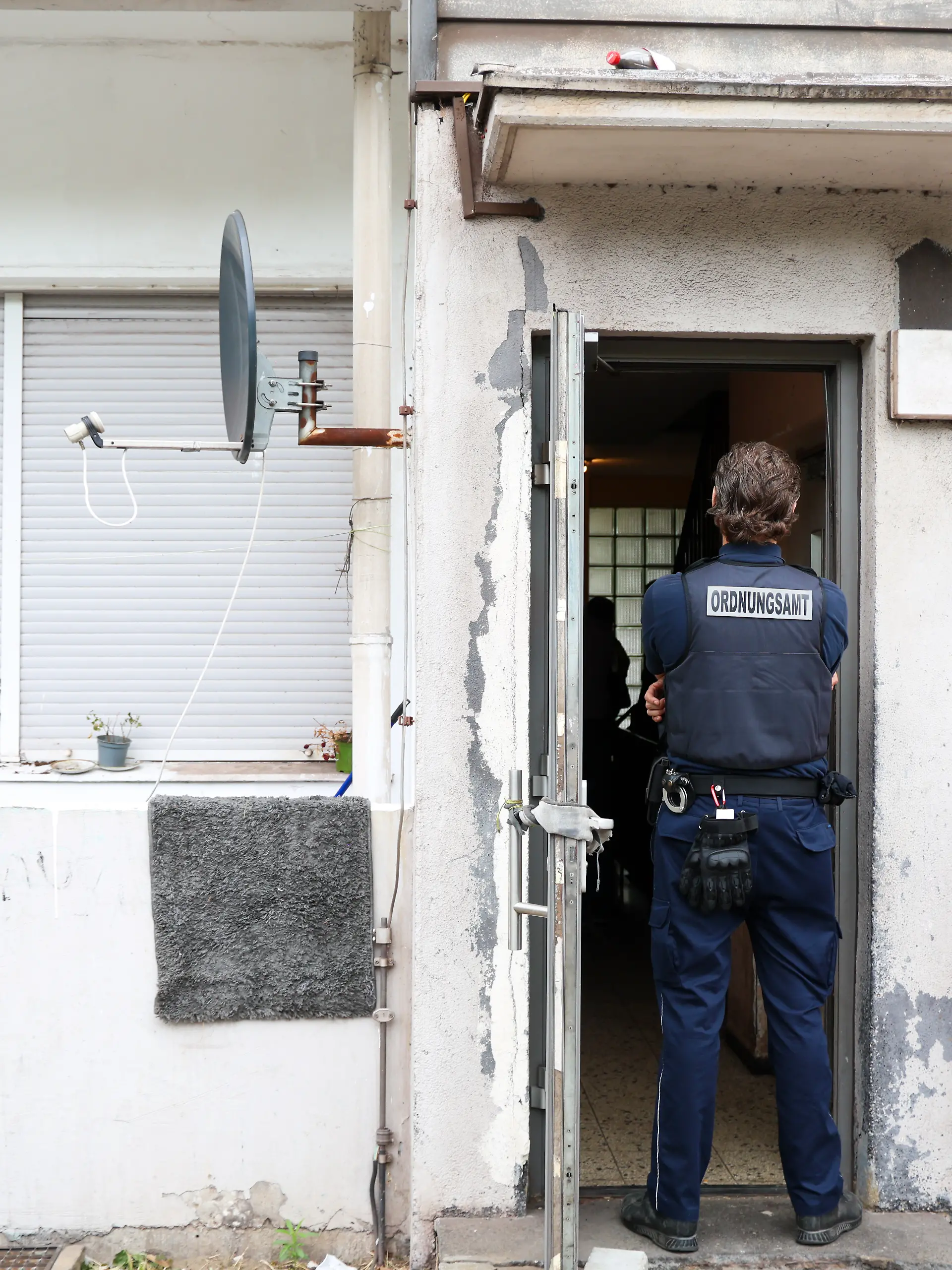 Ein Mitarbeiter vom Ordnungsamt der Stadt Duisburg steht im Eingangsbereich zu einem Wohnhaus, in dem eine Kontrollaktion stattfindet. In mehreren Städten von Nordrhein-Westfalen fanden Kontrollaktionen gegen Sozialmissbrauch und Geschäften mit Schrottimmobilien statt.xxx (zu dpa: «Problemimmobilien und Sozialbetrug: Kontrollaktion in NRW») +++ dpa-Bildfunk +++