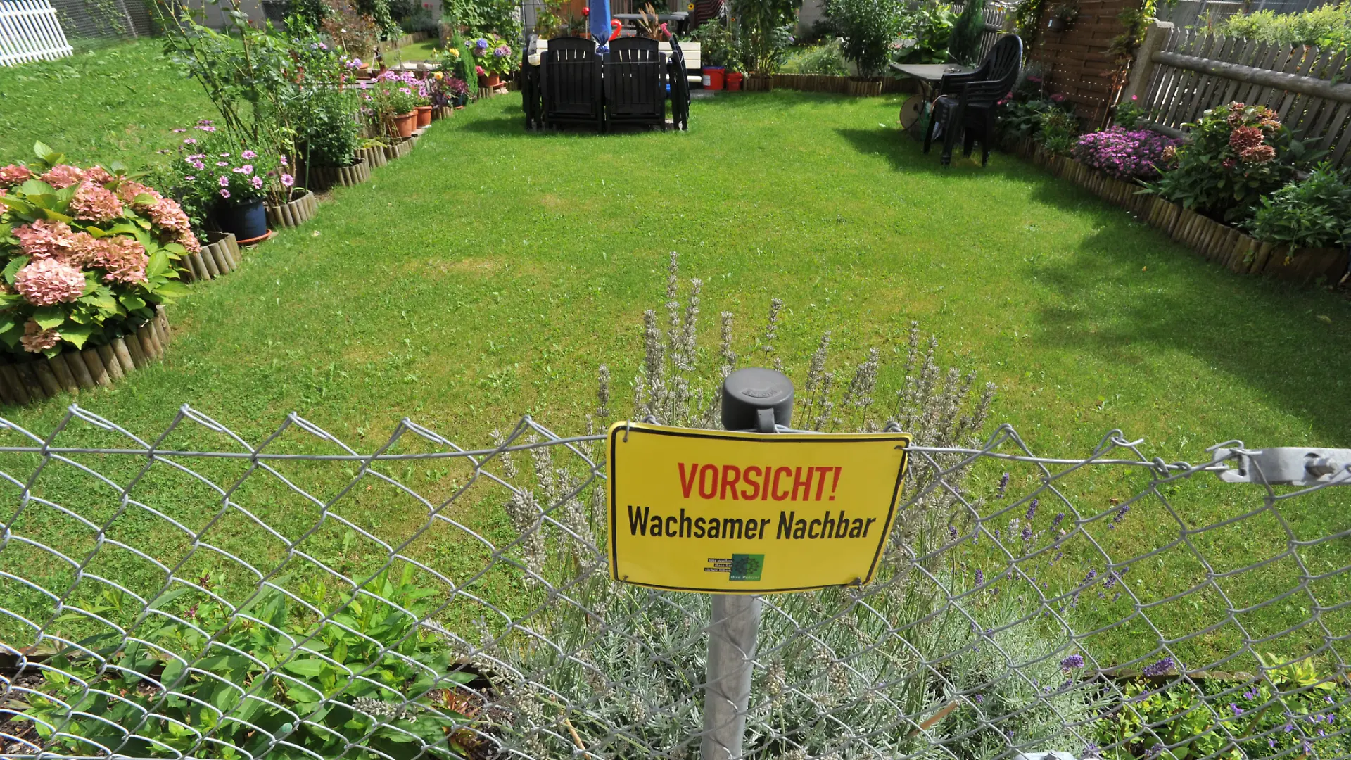 Schild "Vorsicht - Wachsamer Nachbar!" am Gartenzaun eines Wohnhauses in der "Alten Heide" im Münchner Norden., 07.09.2011