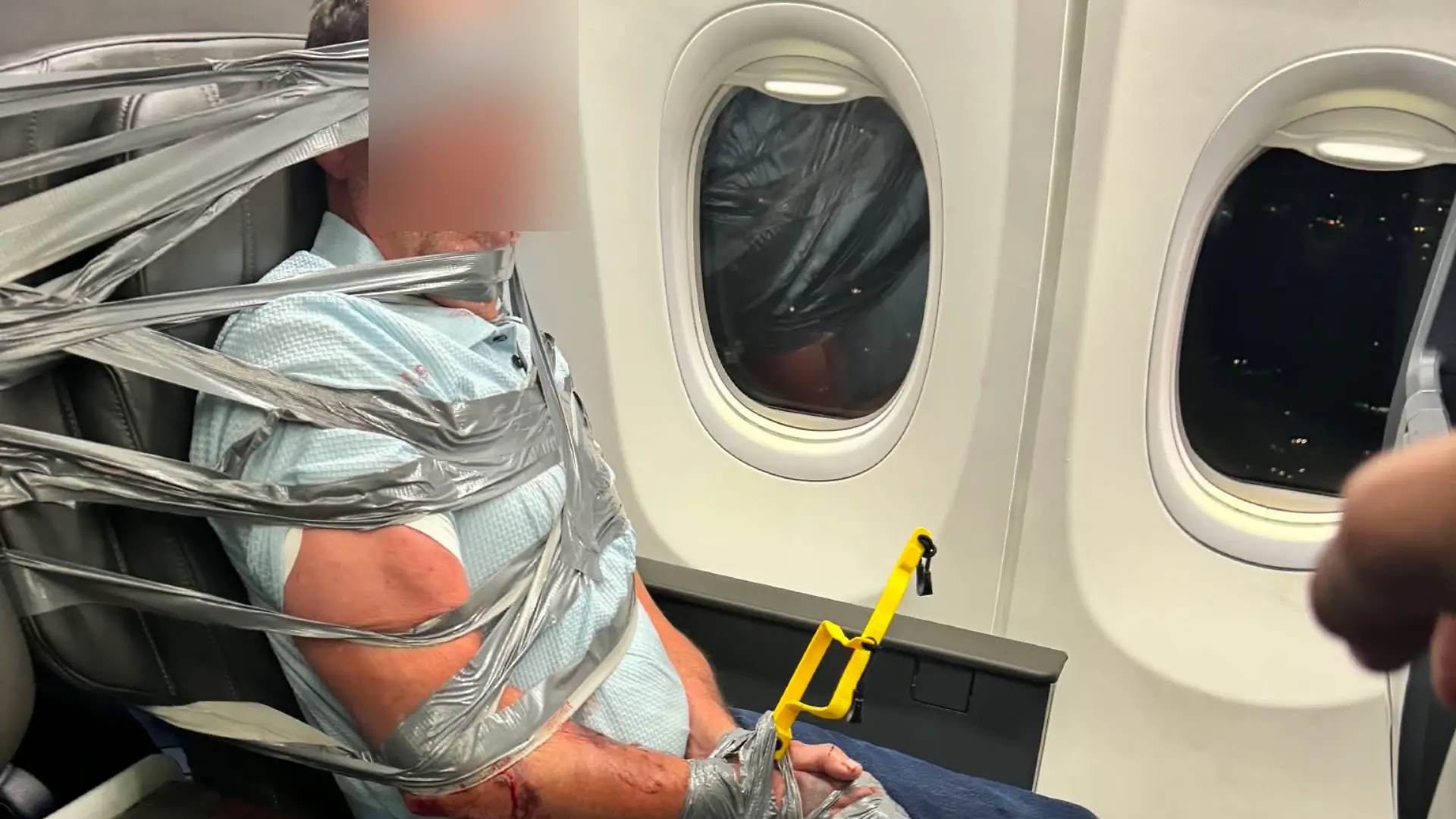 Layne L. mit Klebeband in einem Flugzeugsitz fixiert