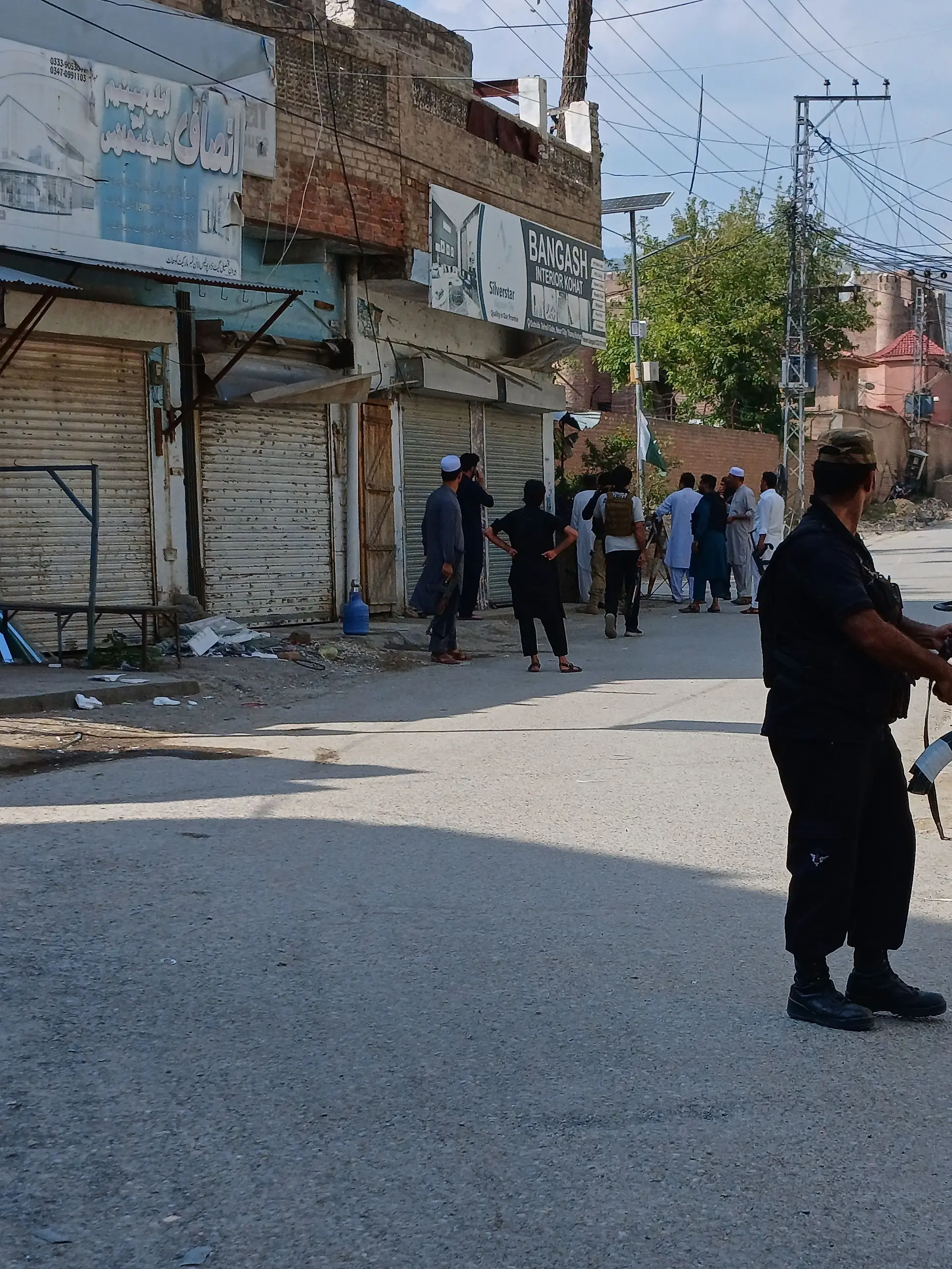 In this photo taken with a smartphone, police officers secure a road leading to the site of a powerful bomb at a mosque in Kohat, Pakistan, Friday, Sept. 18, 2026. (AP Photo/B.S. Gillani)