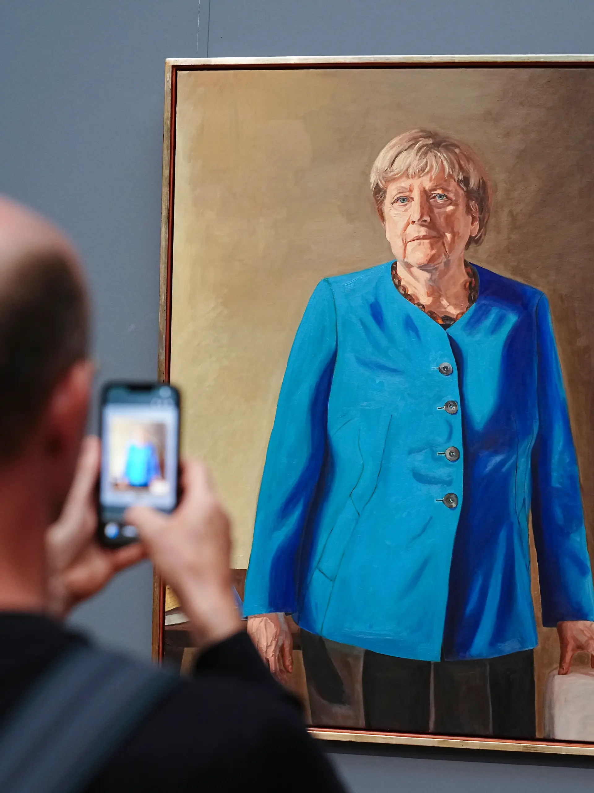 Eine Besucherin macht mit dem Smartphone ein Foto vom Porträt der früheren Kanzlerin Merkel, das von Künstler Jérémie Queyras gezeichnet wurde für die Ahnengalerie im Bundeskanzleramt. Das Bild wird im Bode-Museum nun noch bis Anfang 2027 ausgestellt. (zu dpa: «Großer Andrang: Porträt von Merkel bleibt länger im Museum») +++ dpa-Bildfunk +++