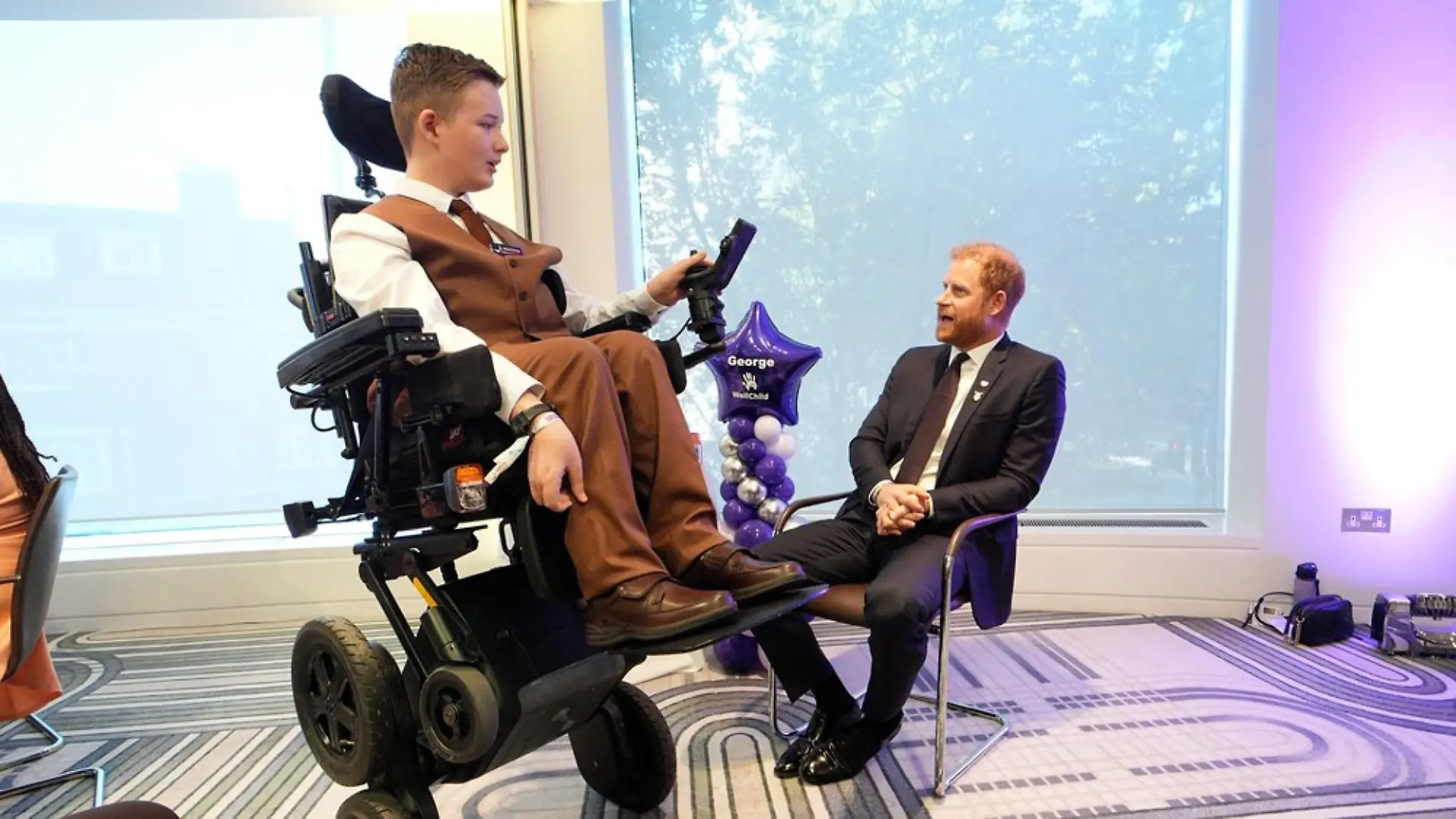 George, einer der jungen Gewinner, zeigt Harry seinen neuen Rollstuhl.