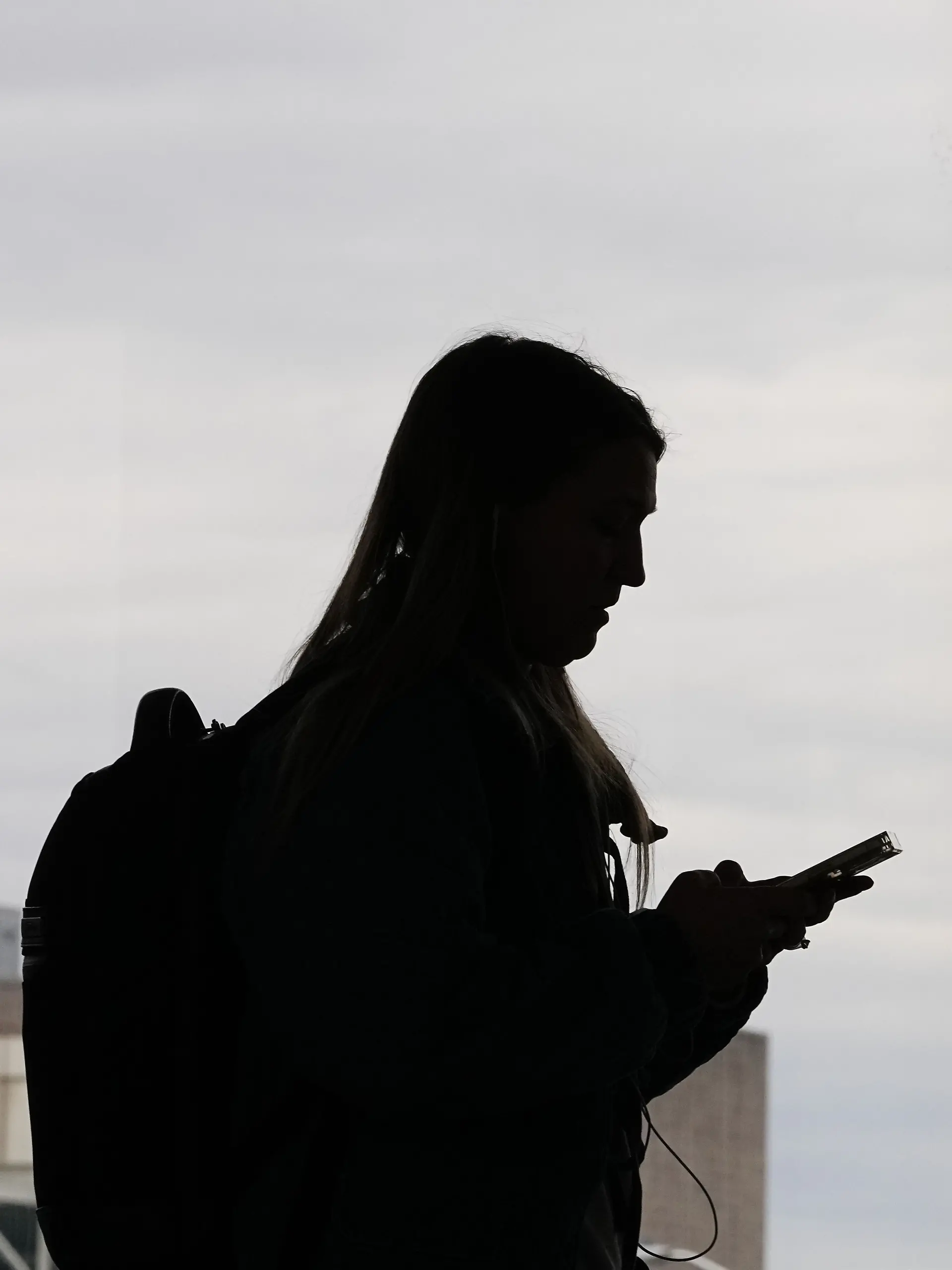 FILE - A traveler with a smartphone walks past an air traffic control tower at Philadelphia International Airport in Philadelphia on March 27, 2026. (AP Photo/Matt Rourke, File)