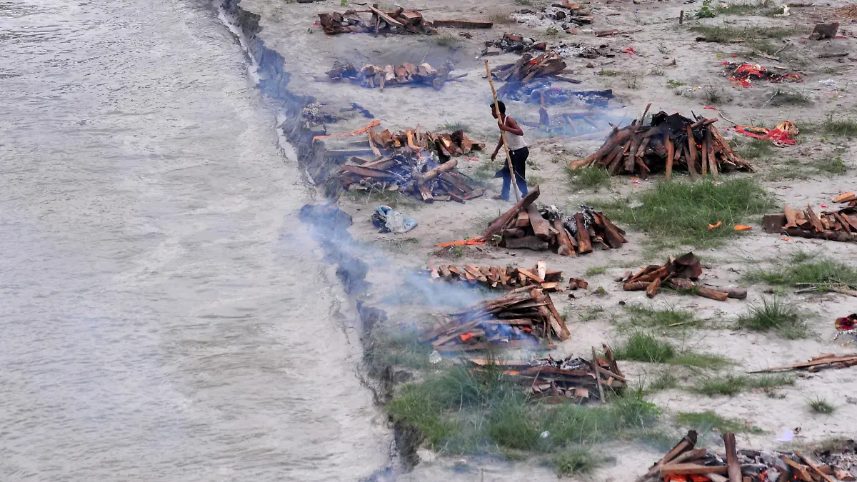 A municipal worker cremates bodies that washed up on the Ganges riverbank after monsoon rains swelled the river and exposed bodies buried in shallow sand graves during the peak of the latest wave of COVID-19 in Phaphamau on the outskirts of Prayagraj, India, June 25, 2021. REUTERS/Ritesh Shukla