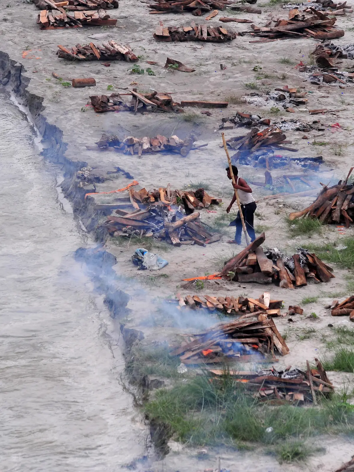 A municipal worker cremates bodies that washed up on the Ganges riverbank after monsoon rains swelled the river and exposed bodies buried in shallow sand graves during the peak of the latest wave of COVID-19 in Phaphamau on the outskirts of Prayagraj, India, June 25, 2021. REUTERS/Ritesh Shukla