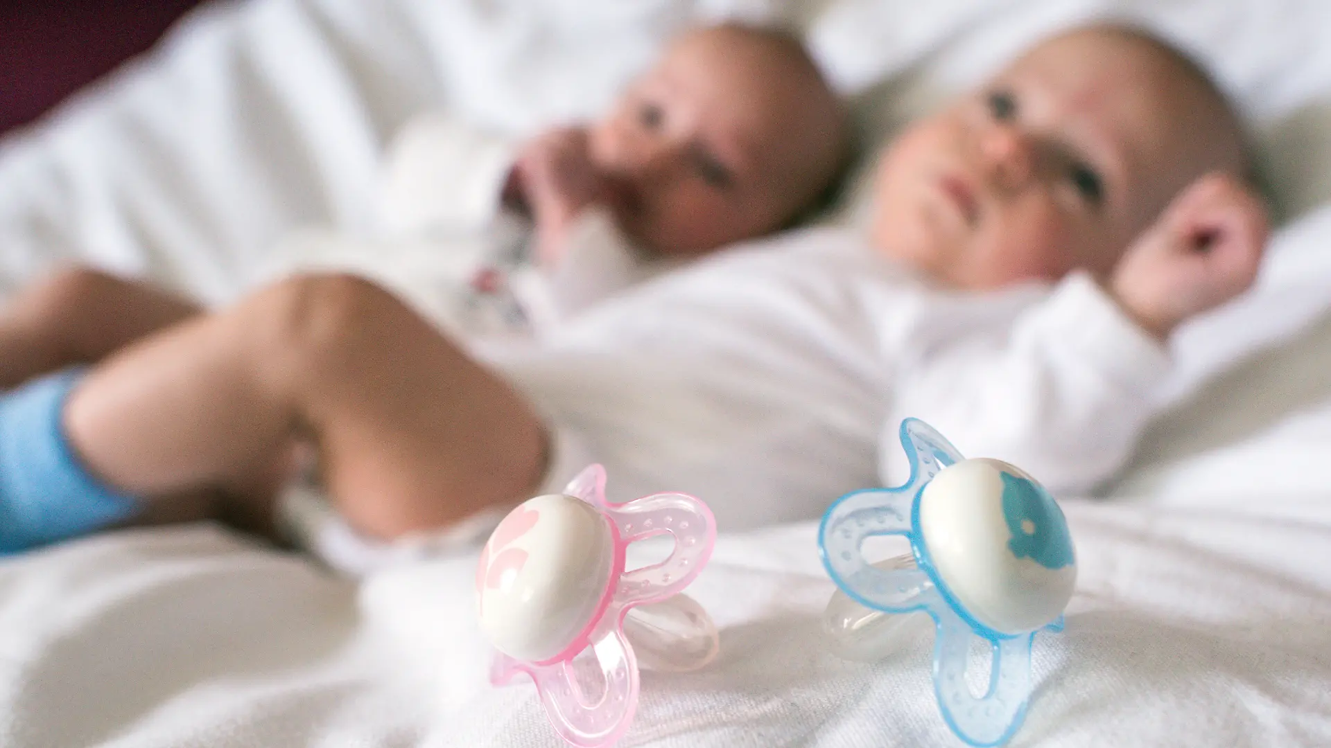 Rosa und blaue Nuckel für ein Mädchen und einen Jungen, aufgenommen in einem Babybettchen in Frankfurt (Oder) (Brandenburg) am 14.04.2015. Foto: Patrick Pleul/dpa