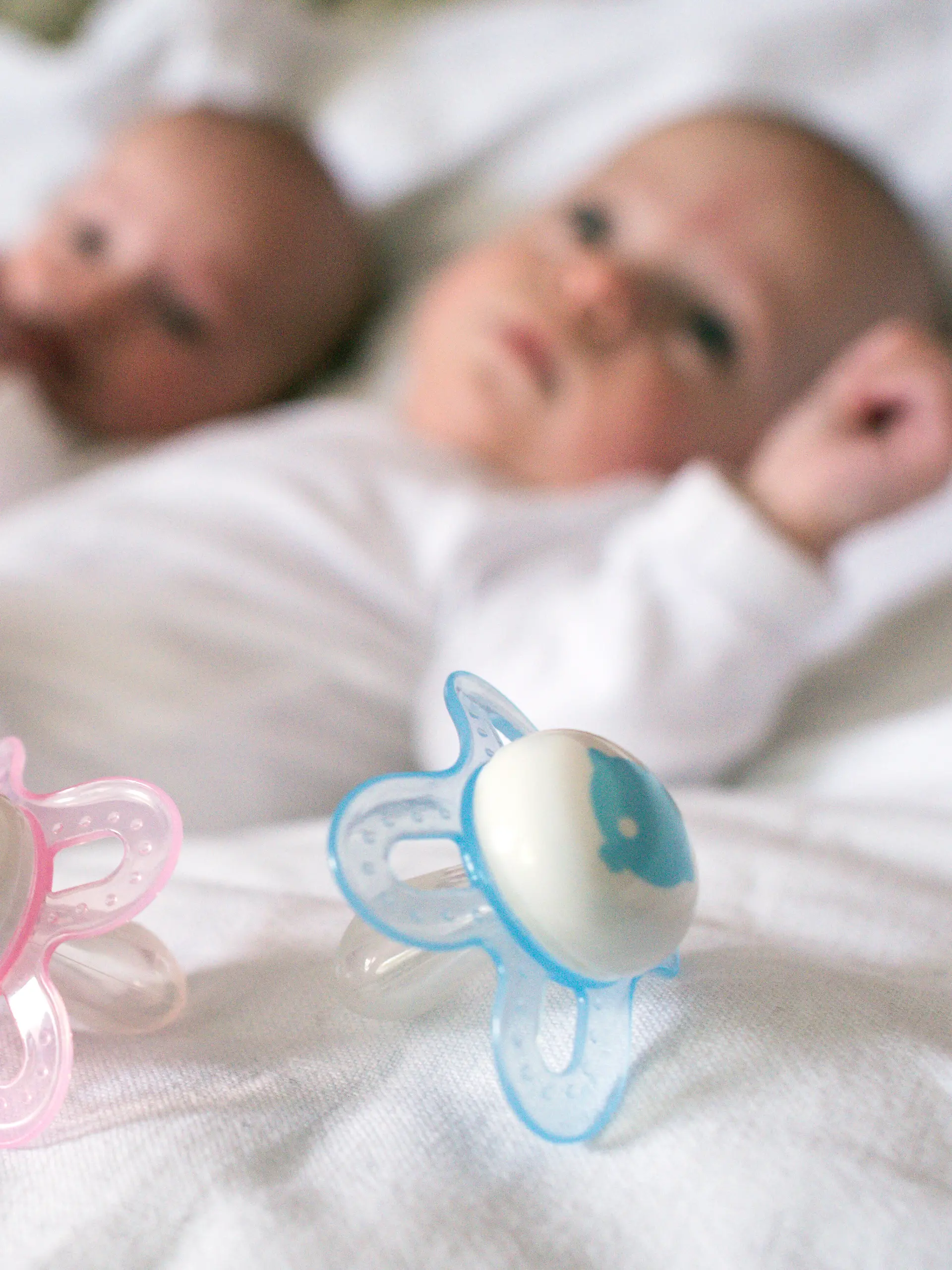 Rosa und blaue Nuckel für ein Mädchen und einen Jungen, aufgenommen in einem Babybettchen in Frankfurt (Oder) (Brandenburg) am 14.04.2015. Foto: Patrick Pleul/dpa