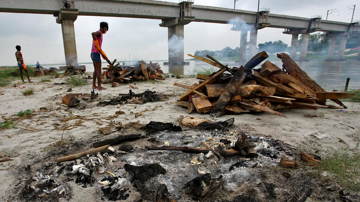 A municipal worker cremates bodies that washed up on the Ganges riverbank after monsoon rains swelled the river and exposed bodies buried in shallow sand graves during the peak of the latest wave of COVID-19 in Phaphamau on the outskirts of Prayagraj, India, June 25, 2021. REUTERS/Ritesh Shukla