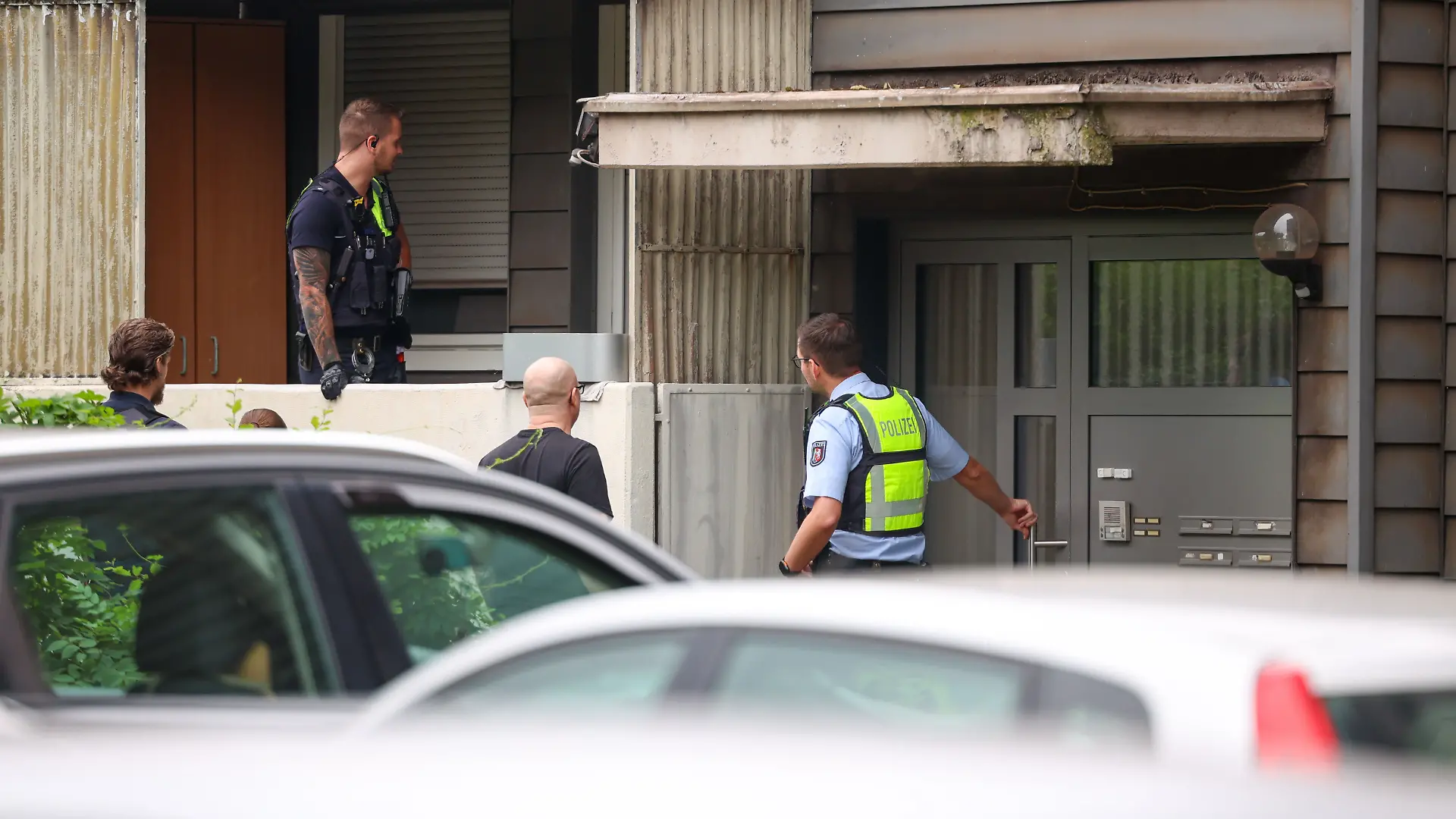 Polizeibeamte stehen bei einer Kontrollaktionen gegen Sozialmissbrauch und Geschäften mit Schrottimmobilien in Duisburg auf einem Balkon und vor einem Haus.