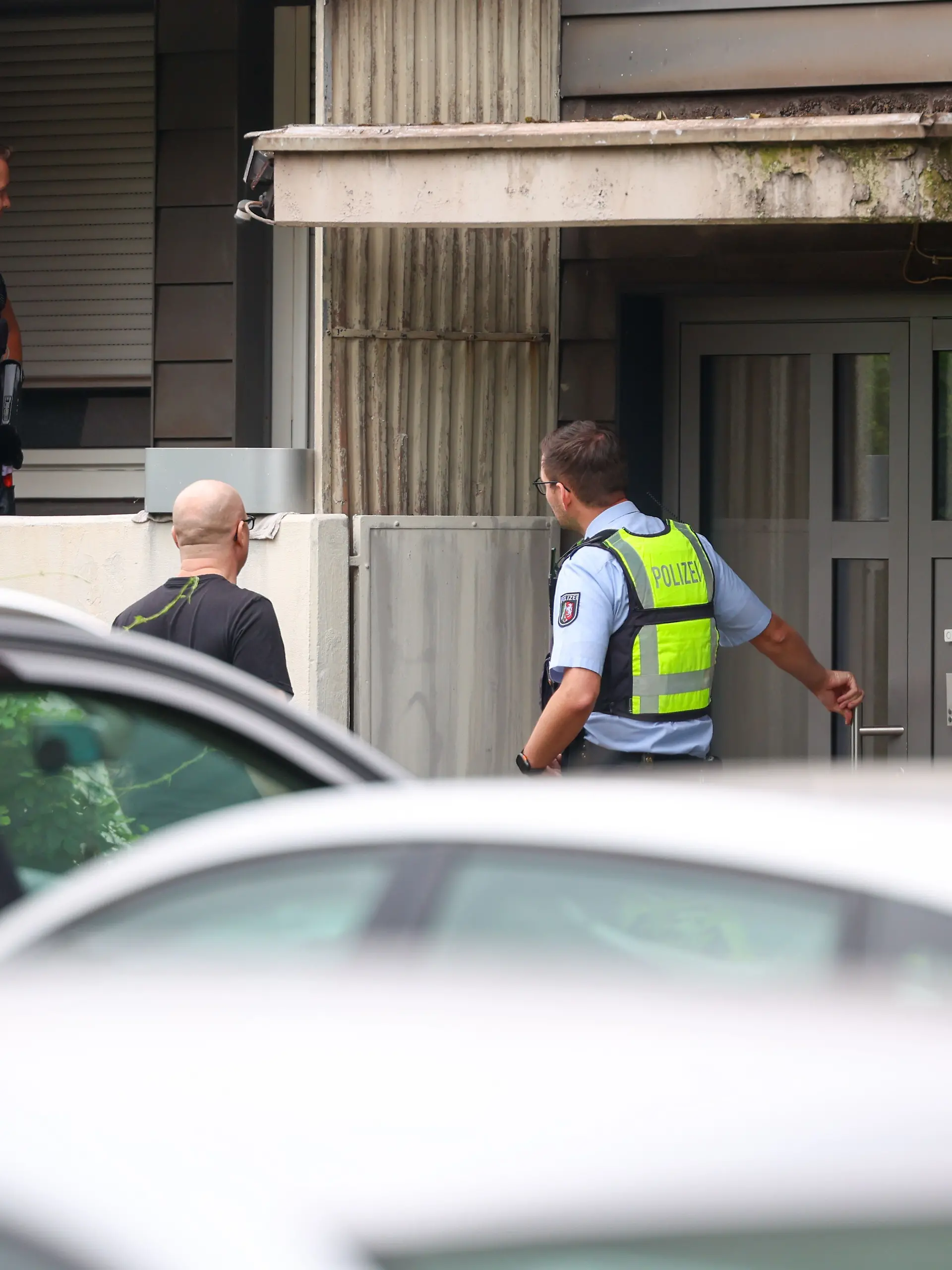 Polizeibeamte stehen bei einer Kontrollaktionen gegen Sozialmissbrauch und Geschäften mit Schrottimmobilien in Duisburg auf einem Balkon und vor einem Haus.