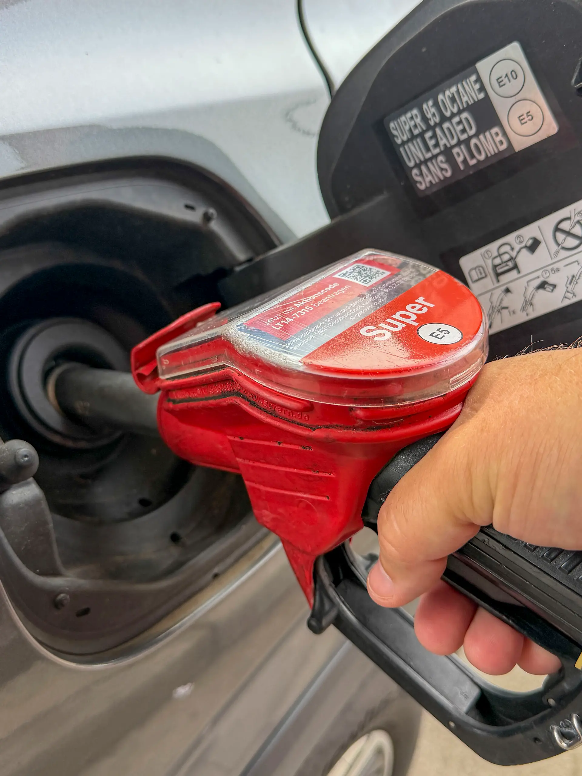 Ein Autofahrer hält eine Zapfpistole beim Betanken eines Autos an einer Tankstelle. Das Symbolfoto steht für Tanken, Kraftstoff, Benzinpreise, Mobilität und steigende Kosten im Straßenverkehr.