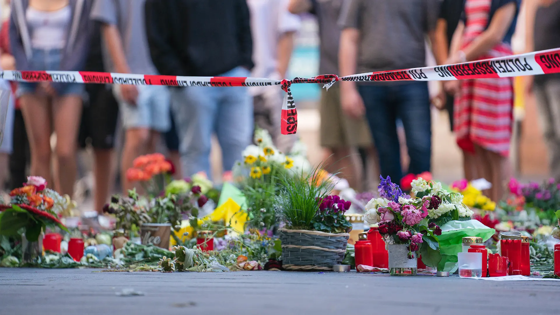 28.06.2021, Bayern, Würzburg: Trauerkerzen und Blumen liegen vor einem Kaufhaus in der Innenstadt, in dem ein Mann Menschen mit einem Messer attackiert hatte. Bei dem Angriff am 25.06.2021 hatte ein Somalier drei Frauen in einem Kaufhaus getötet. Auf der Straße und in einer nahen Bank verletzte er danach laut Polizei sechs Menschen schwer und einen leicht. Foto: Nicolas Armer/dpa +++ dpa-Bildfunk +++