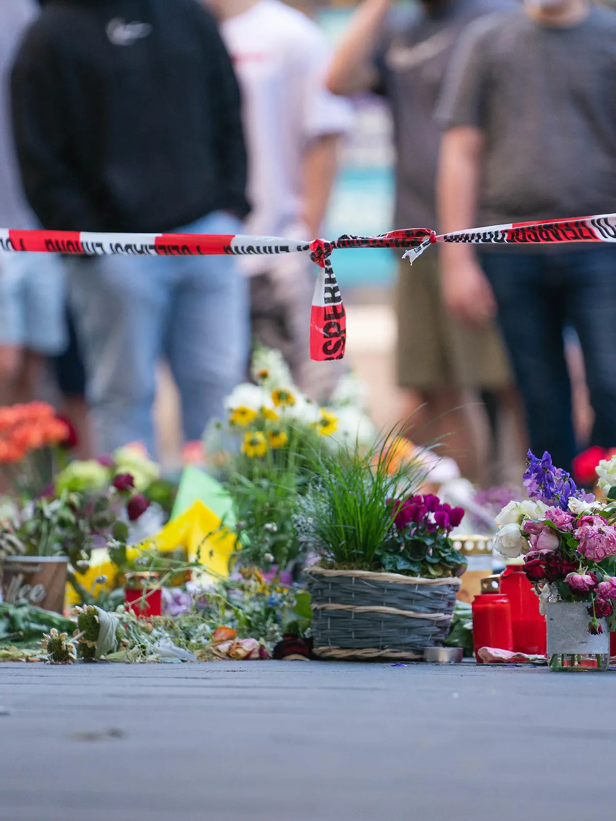 28.06.2021, Bayern, Würzburg: Trauerkerzen und Blumen liegen vor einem Kaufhaus in der Innenstadt, in dem ein Mann Menschen mit einem Messer attackiert hatte. Bei dem Angriff am 25.06.2021 hatte ein Somalier drei Frauen in einem Kaufhaus getötet. Auf der Straße und in einer nahen Bank verletzte er danach laut Polizei sechs Menschen schwer und einen leicht. Foto: Nicolas Armer/dpa +++ dpa-Bildfunk +++