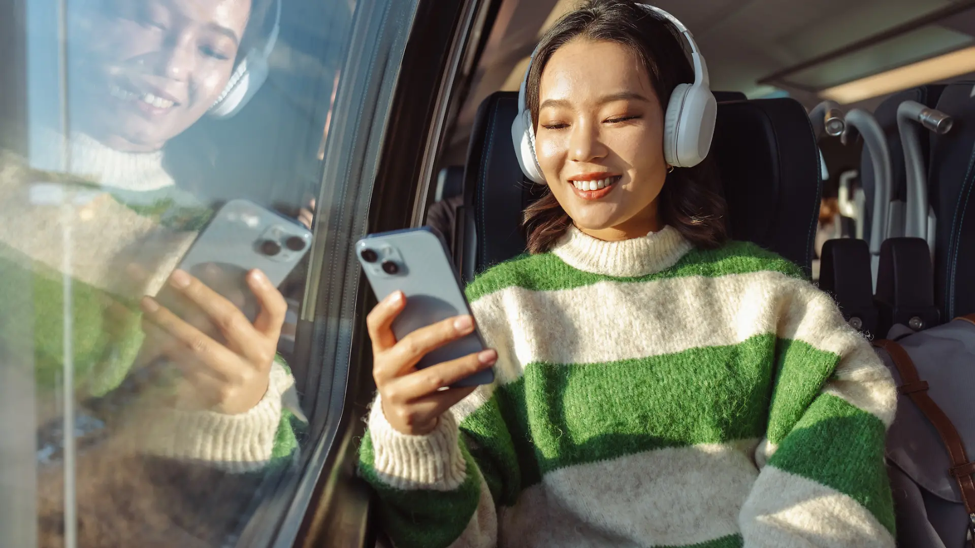 Eine Frau sitzt in einer Bahn und schaut auf ihr Smartphone.
