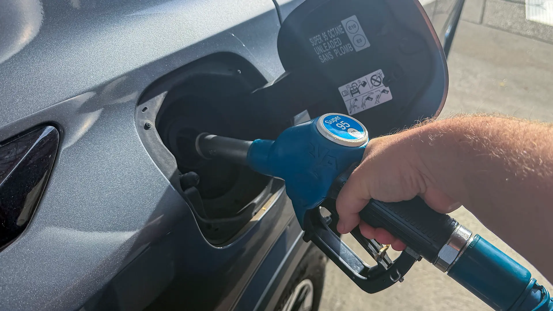 Ein Autofahrer hält eine Zapfpistole beim Betanken eines Autos an einer Tankstelle. Das Symbolfoto steht für Tanken, Kraftstoff, Benzinpreise, Mobilität und steigende Kosten im Straßenverkehr.