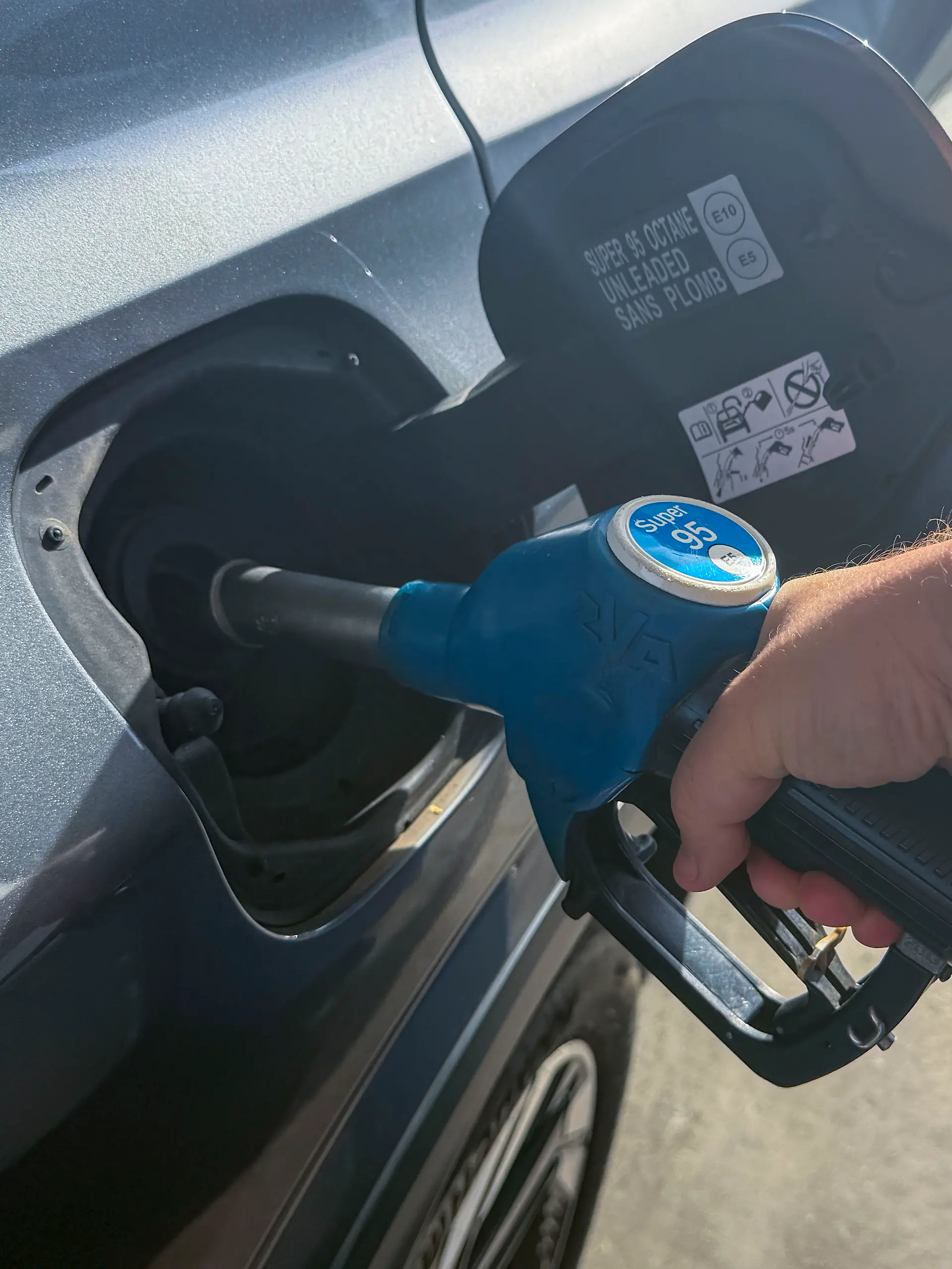 Ein Autofahrer hält eine Zapfpistole beim Betanken eines Autos an einer Tankstelle. Das Symbolfoto steht für Tanken, Kraftstoff, Benzinpreise, Mobilität und steigende Kosten im Straßenverkehr.