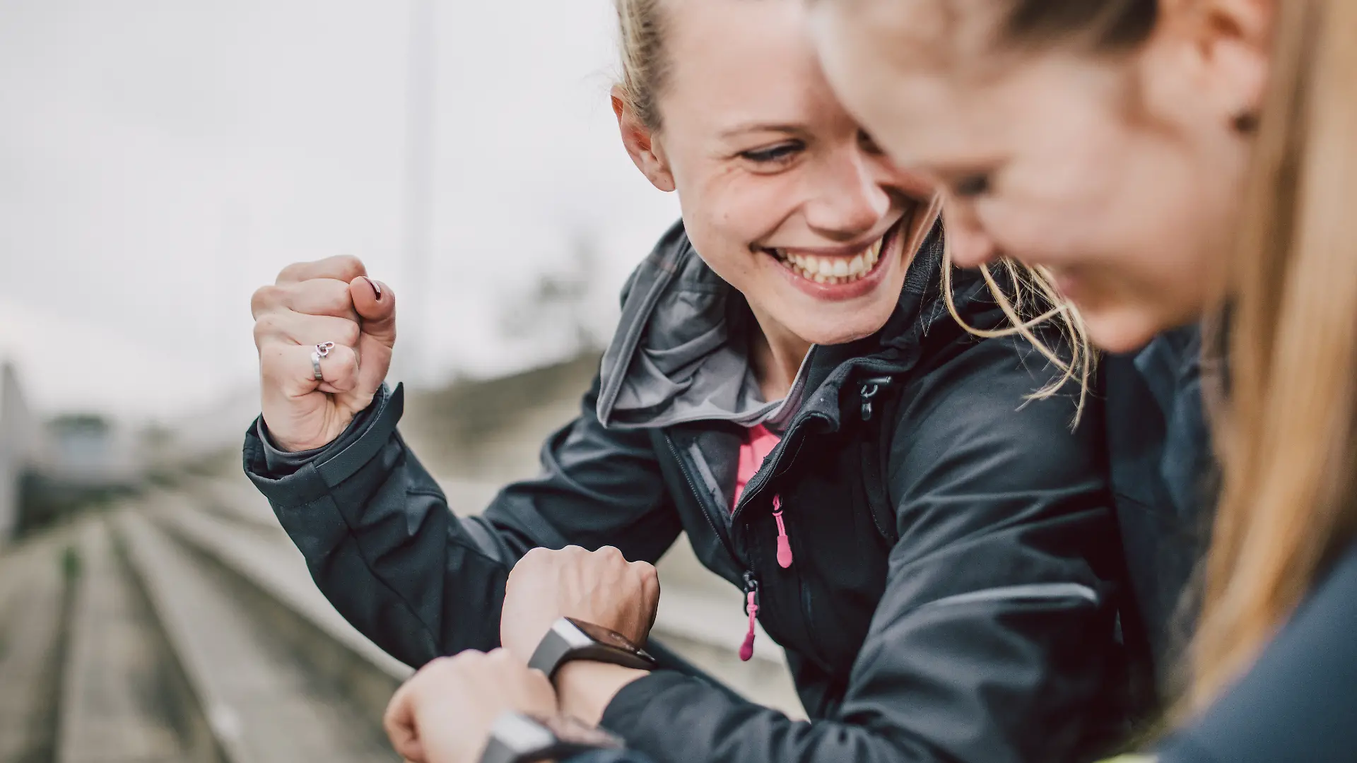 Freundinnen, die nach dem Sport über ihre Smartwatch ihre Daten vergleichen