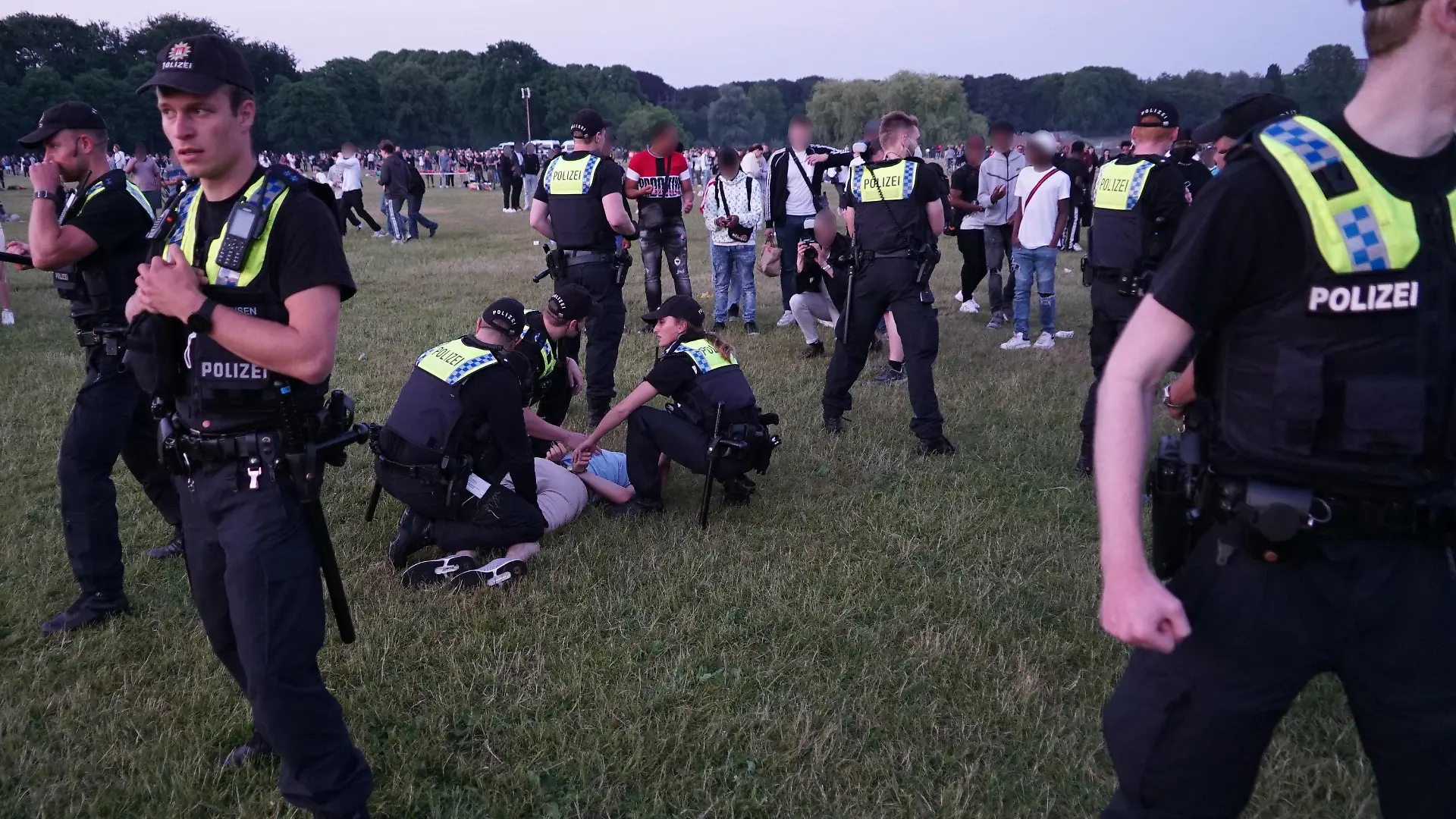 25.06.2021, Hamburg: Die Polizei löst eine Menschenansammlung im Stadtpark auf. Zu Spitzenzeiten seien bis zu 4000 Besucher dort gewesen, teilte die Polizei mit. Es habe fünf Ingewahrsamnahmen und sechs Festnahmen gegeben. Drei Beamte seien bei dem Einsatz leicht verletzt worden. (zu dpa "Festnahmen und Verletzte bei Polizeieinsatz im Hamburger Stadtpark") Foto: -/Citynews TV/dpa - ACHTUNG: Personen wurden aus rechtlichen Gründen gepixelt +++ dpa-Bildfunk +++
