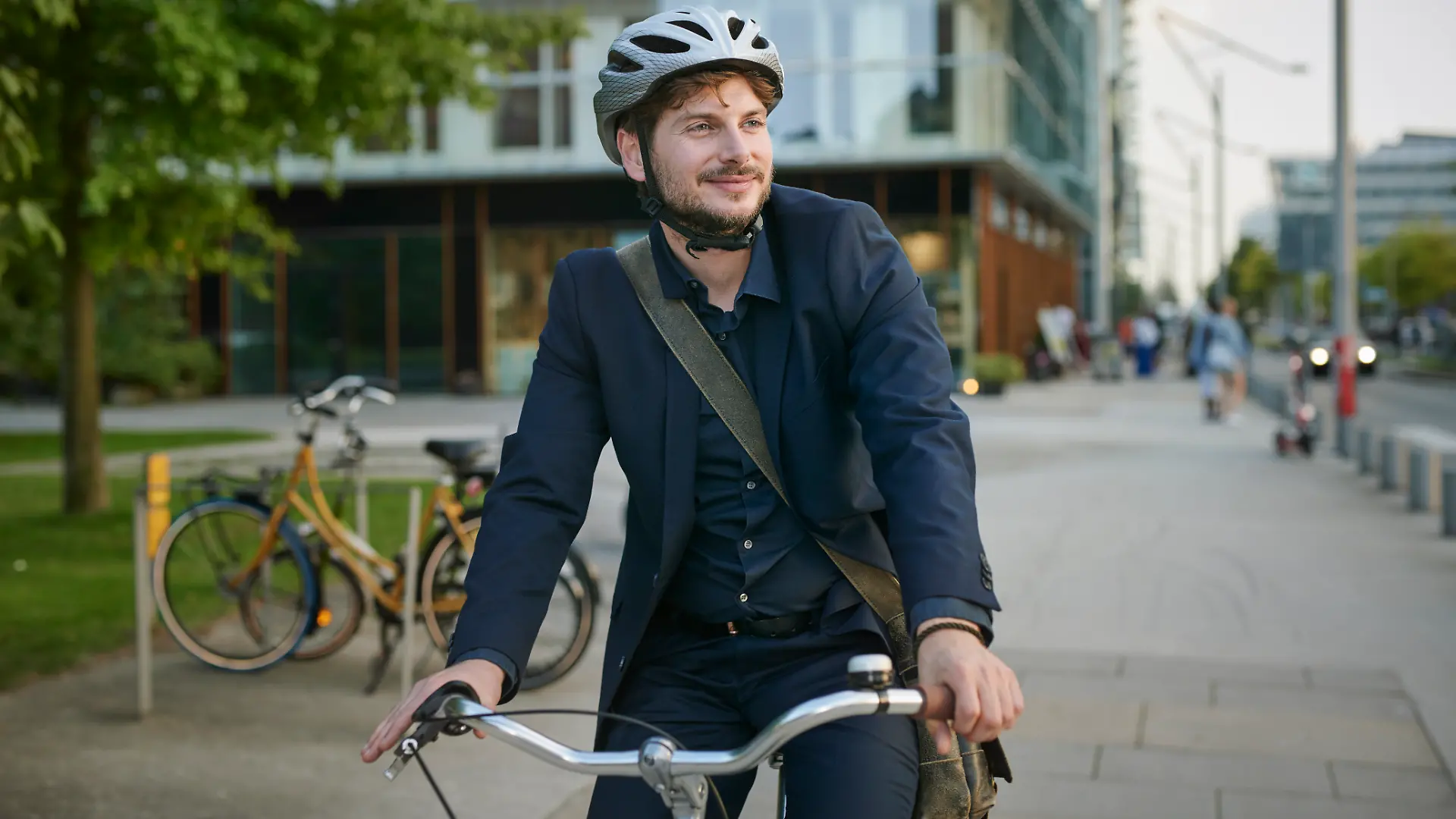 Mann im Anzug und mit Fahrradhelm sitzt auf einem Fahrrad.