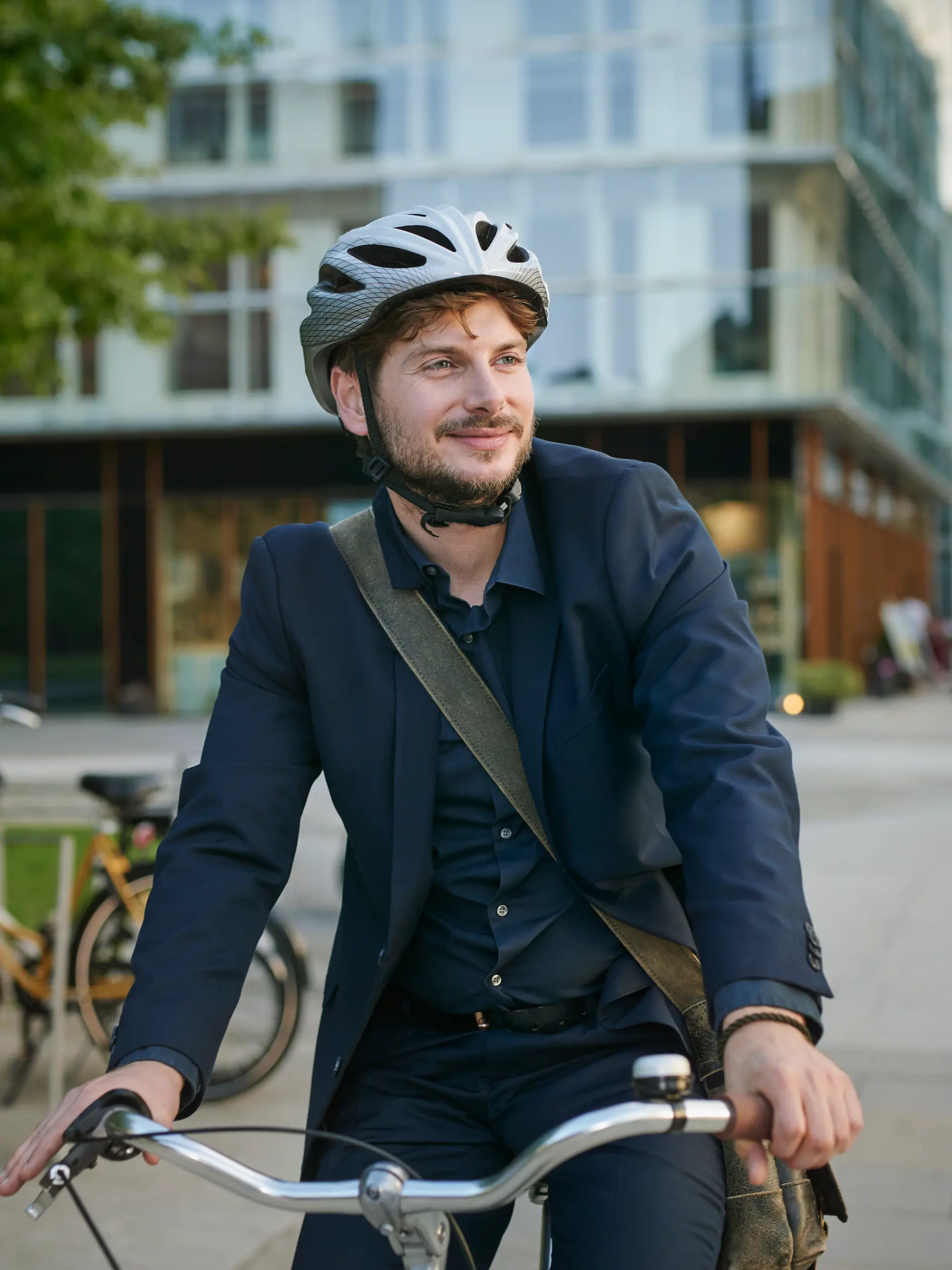 Mann im Anzug und mit Fahrradhelm sitzt auf einem Fahrrad.