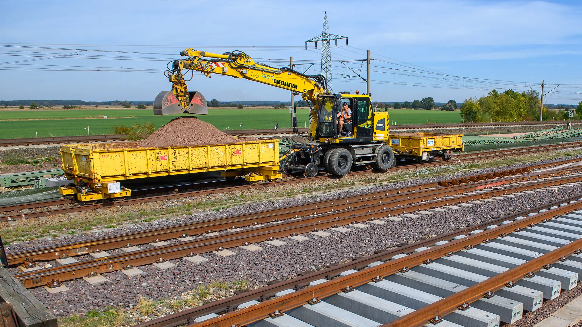 Ein Gleisbaufahrzeug rollt nahe des Bahnhofs Schönhausen an Gleisbauteilen vorbei. Die "DB InfraGO" startet am 2. Oktober 2026 mit den Bauarbeiten entlang der Ost-West-Achse zwischen Hannover und Berlin. In den kommenden Monaten wird auf der Schnellfahrstrecke östlich und westlich von Stendal die Feste Fahrbahn erneuert. Gleichzeitig wird die Elektrifizierung der parallel verlaufenden Lehrter Stammbahn weitergebaut.