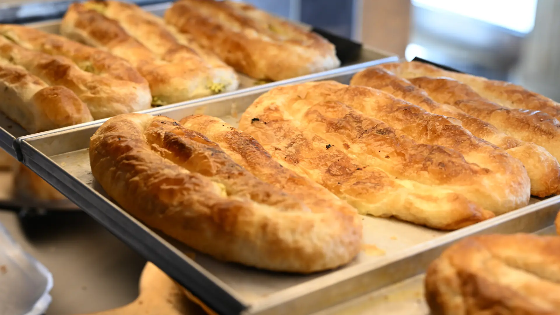 Unterschiedliche Backwaren liegen in der Theke. Im Vordergrund liegt Börek