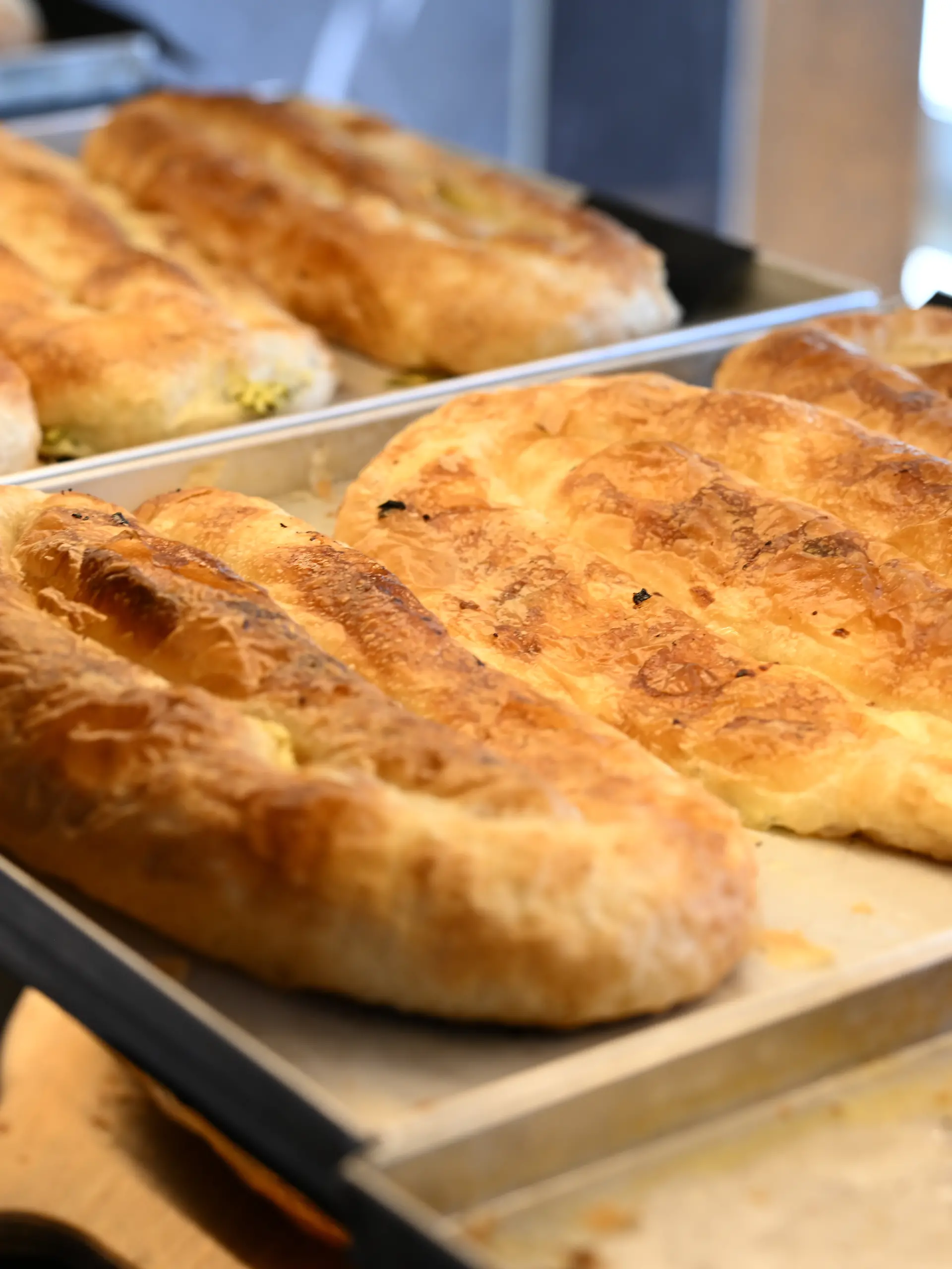 Unterschiedliche Backwaren liegen in der Theke. Im Vordergrund liegt Börek