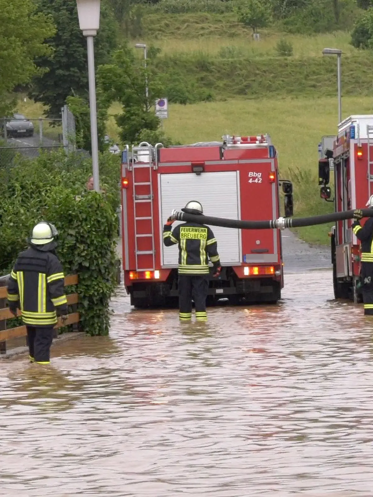 29.06.2021, Hessen, Breuberg (Odenwald): Einsatzkräfte der Feuerwehr stehen auf einer durch ein Unwetter überfluteten Straße. Foto: Alexander Keutz/Keutz TV-NEWS/dpa +++ dpa-Bildfunk +++