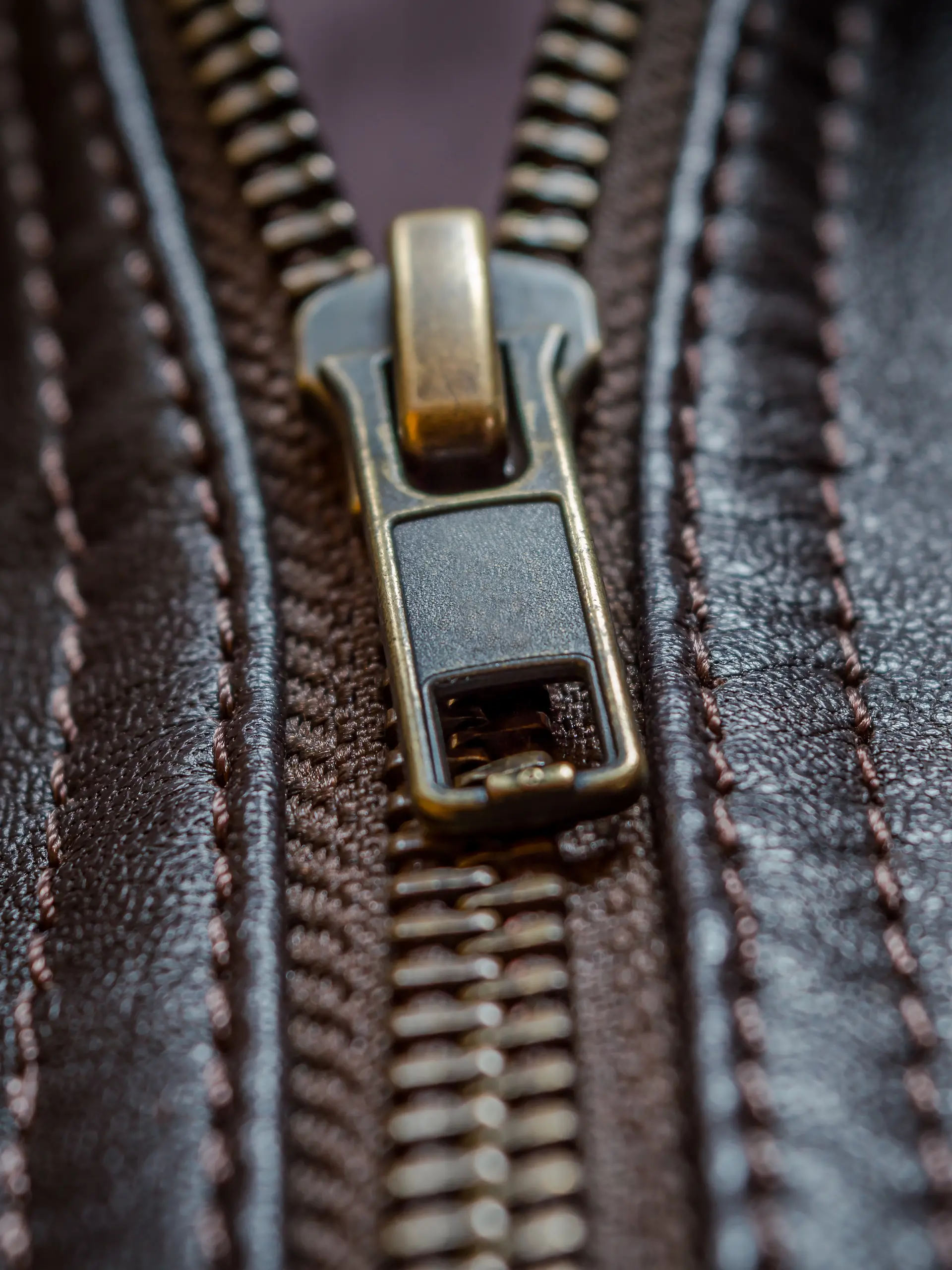 Close-up des Reißverschlusses einer dunkelbraunen Lederjacke 