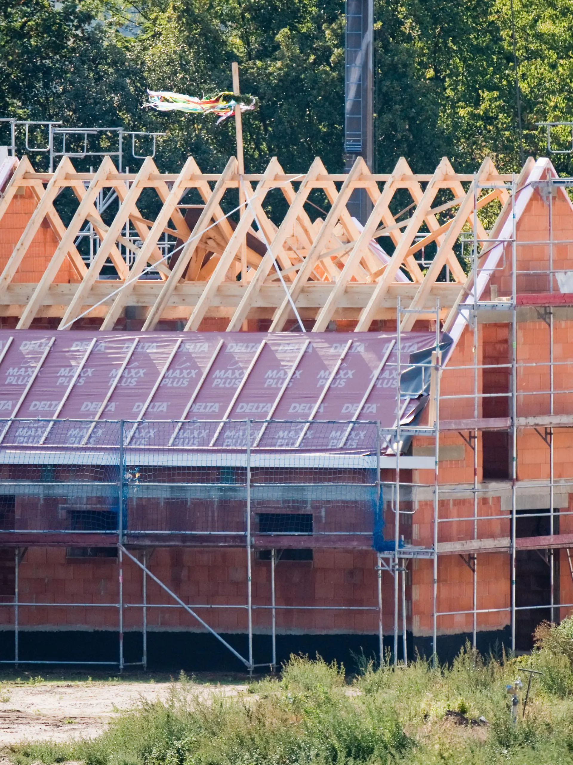 Ein Richtkranz weht am Dachstuhl eines neu gebauten Einfamilienhauses in einer Neubausiedlung in der Region Hannover.