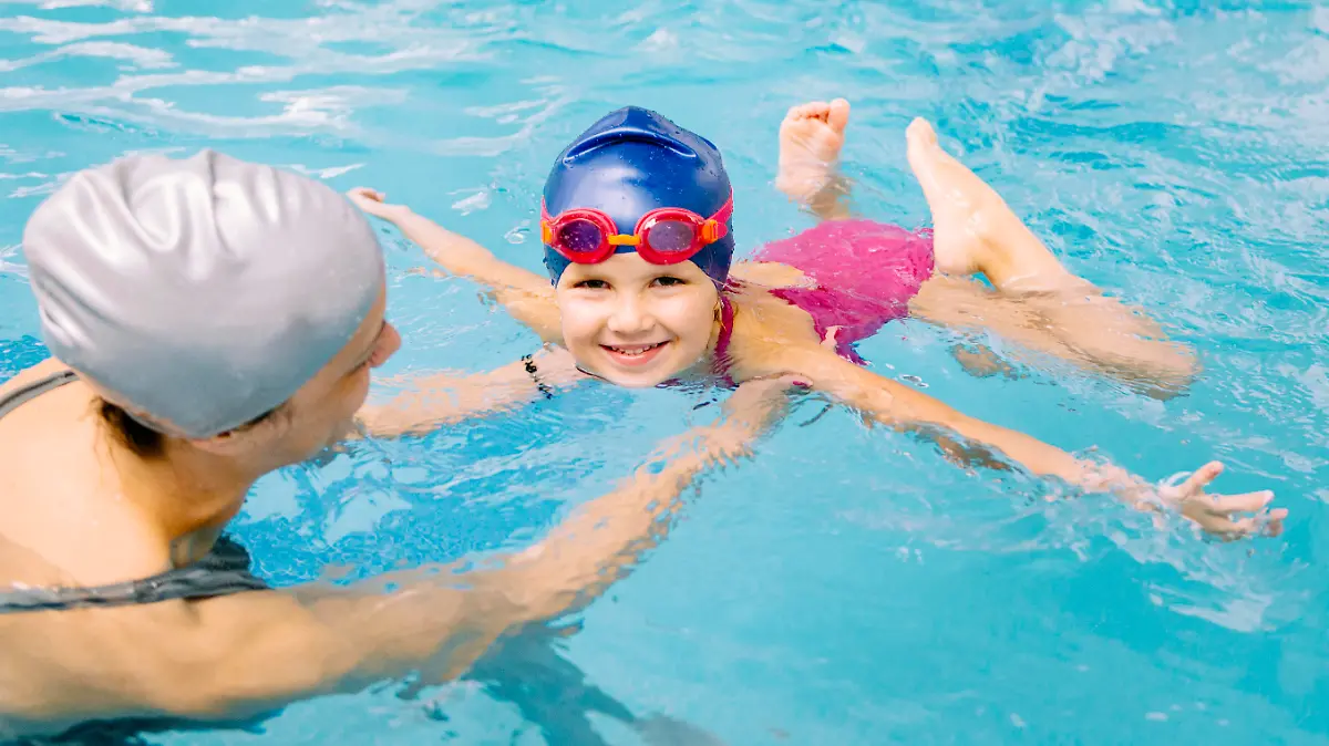 Swimming class - little girl learning to swim with swimming  instructor