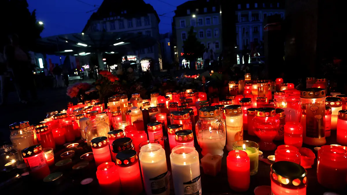 26.06.2021, Bayern, Würzburg: Blumen und Kerzen vor einem geschlossenen und abgesperrten Kaufhaus in der Innenstadt. Nach der Bluttat in Würzburg, bei der ein Mann wahllos Menschen mit einem Messer attackiert hat, ist Ruhe eingekehrt. Menschen hielten im Vorbeigehen inne und legten auch in den Abendstunden Blumen nieder. Polizisten standen noch immer vor einem abgesperrten Tatort. Foto: Karl-Josef Hildenbrand/dpa +++ dpa-Bildfunk +++