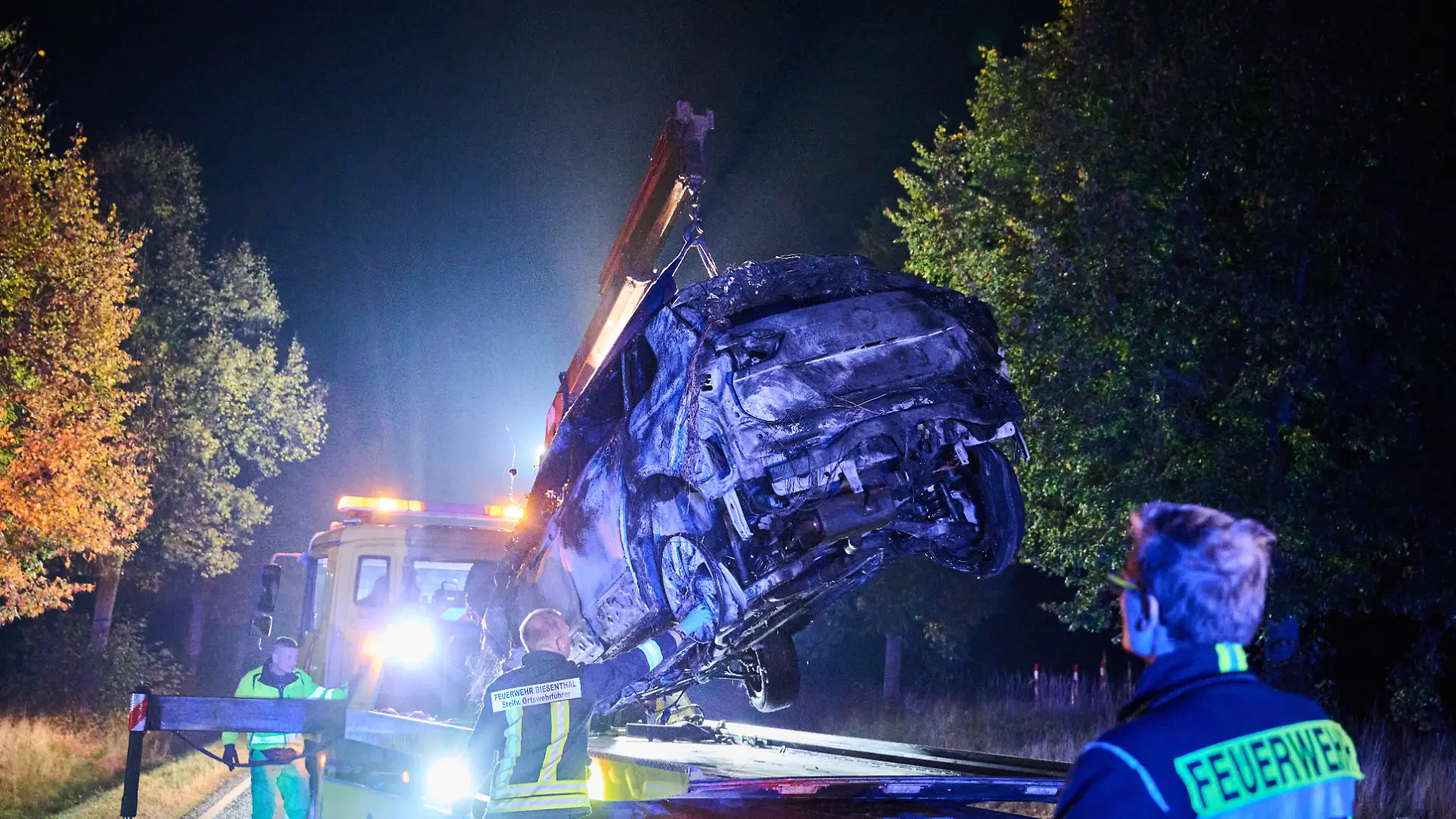 Ein Abschleppen hebt ein verbranntes Auto auf seinen Transporter. Beim Frontalzusammenstoß eines Autos mit drei Mopeds sind in Brandenburg vier Menschen ums Leben gekommen. Der Unfall passierte am Abend bei Biesenthal im Landkreis Barnim, wie die Polizei mitteilte.