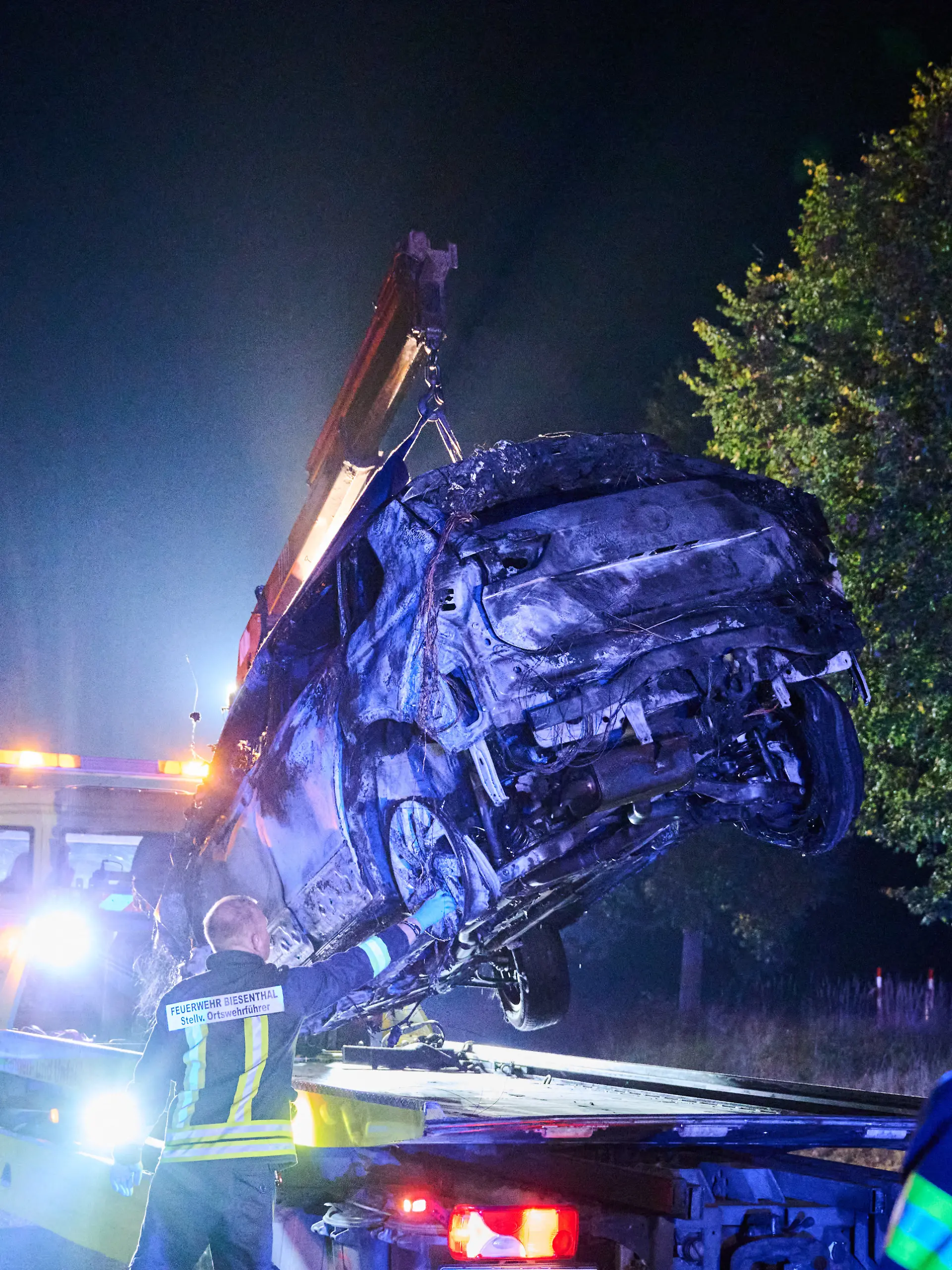 Ein Abschleppen hebt ein verbranntes Auto auf seinen Transporter. Beim Frontalzusammenstoß eines Autos mit drei Mopeds sind in Brandenburg vier Menschen ums Leben gekommen. Der Unfall passierte am Abend bei Biesenthal im Landkreis Barnim, wie die Polizei mitteilte.