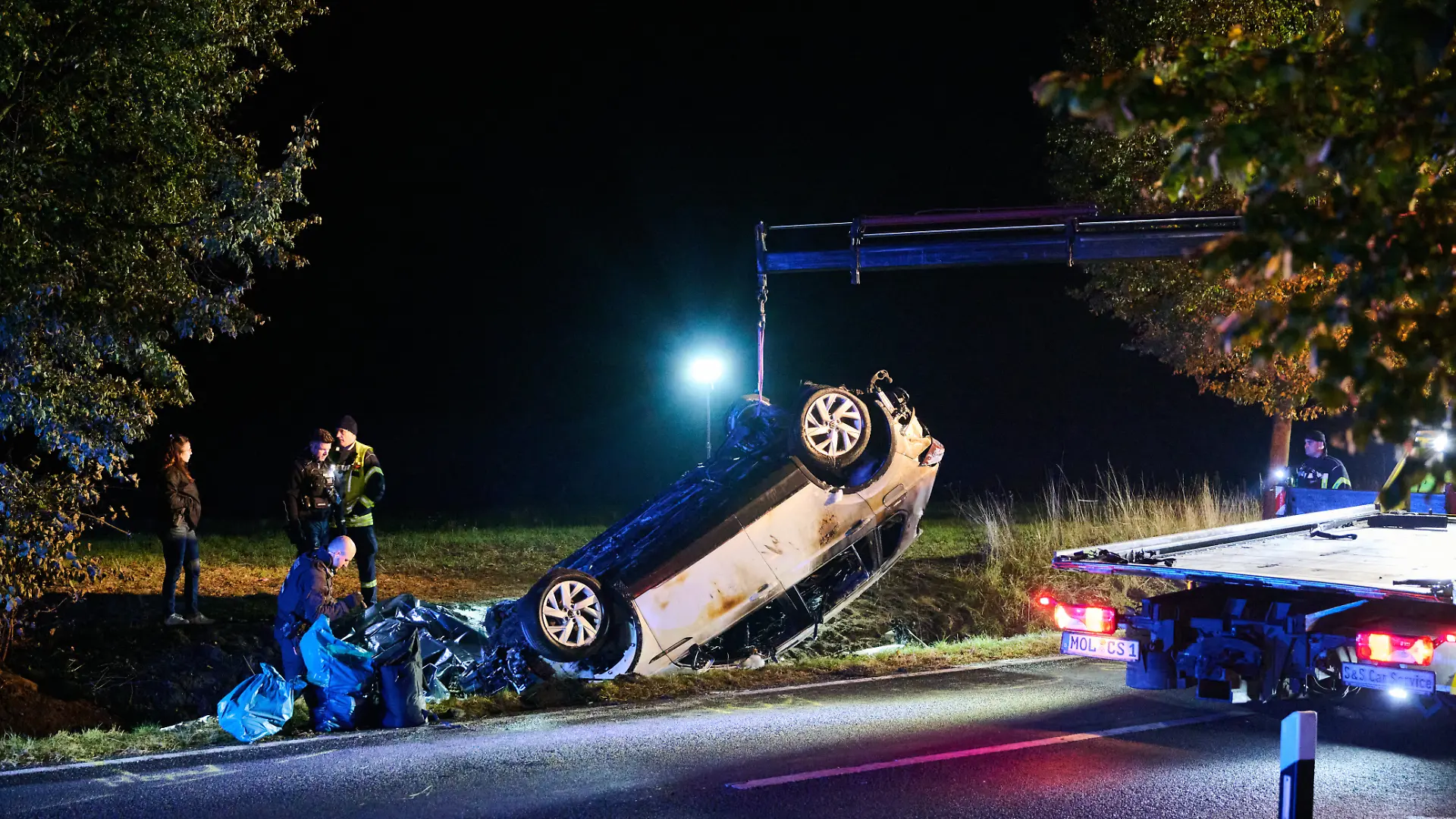 Ein Abschleppen hebt ein verbranntes Auto auf seinen Transporter. Beim Frontalzusammenstoß eines Autos mit drei Mopeds sind in Brandenburg vier Menschen ums Leben gekommen. Der Unfall passierte am Abend bei Biesenthal im Landkreis Barnim, wie die Polizei mitteilte.