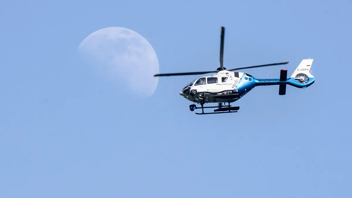 19.06.2021, Bayern, München: Fußball: EM, Portugal - Deutschland, Vorrunde, Gruppe F, 2. Spieltag. Ein Polizeihubschrauber fliegt über dem EM-Stadion während dahinter der Mond zu sehen ist. Foto: Matthias Balk/dpa +++ dpa-Bildfunk +++
