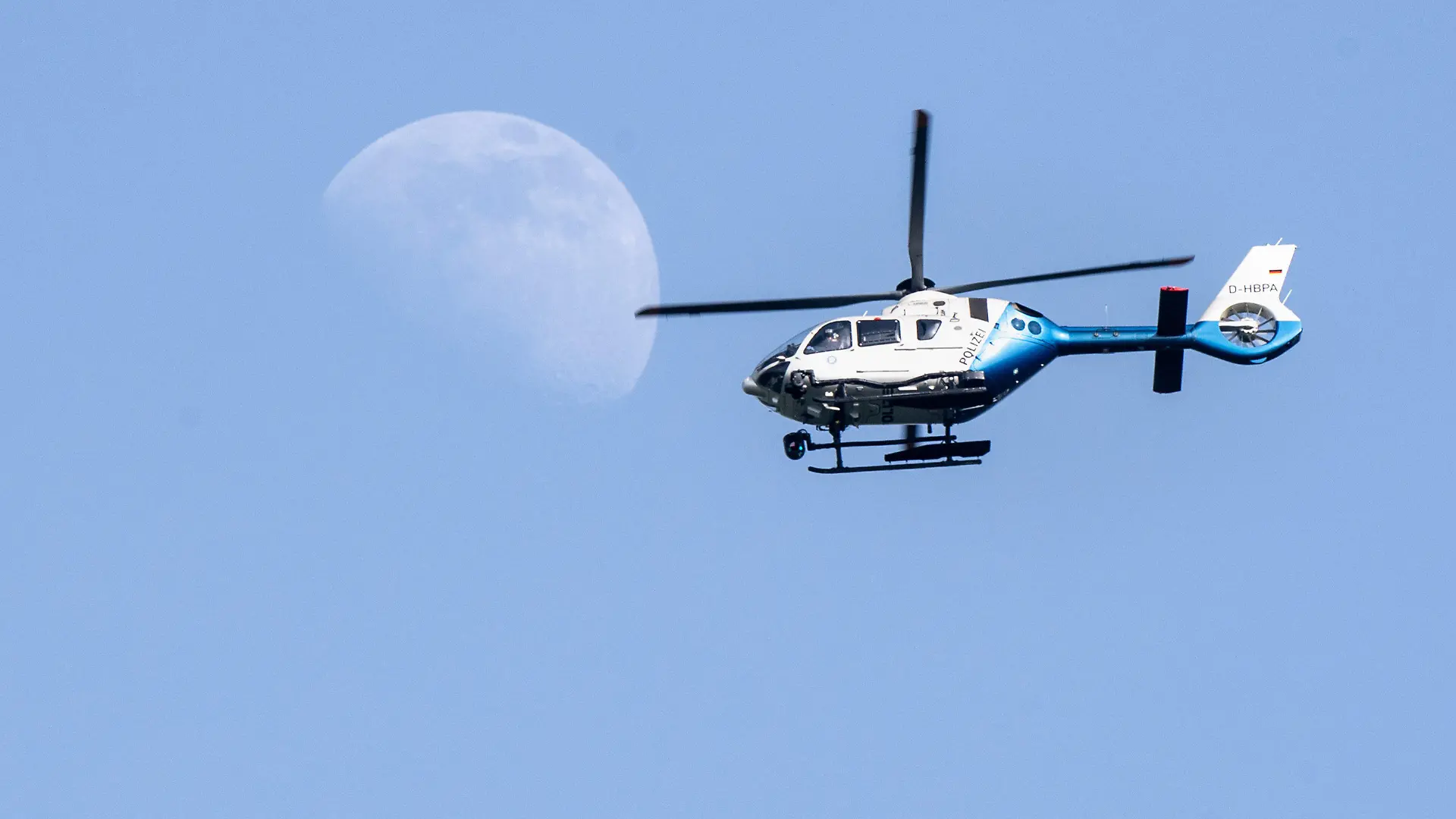19.06.2021, Bayern, München: Fußball: EM, Portugal - Deutschland, Vorrunde, Gruppe F, 2. Spieltag. Ein Polizeihubschrauber fliegt über dem EM-Stadion während dahinter der Mond zu sehen ist. Foto: Matthias Balk/dpa +++ dpa-Bildfunk +++