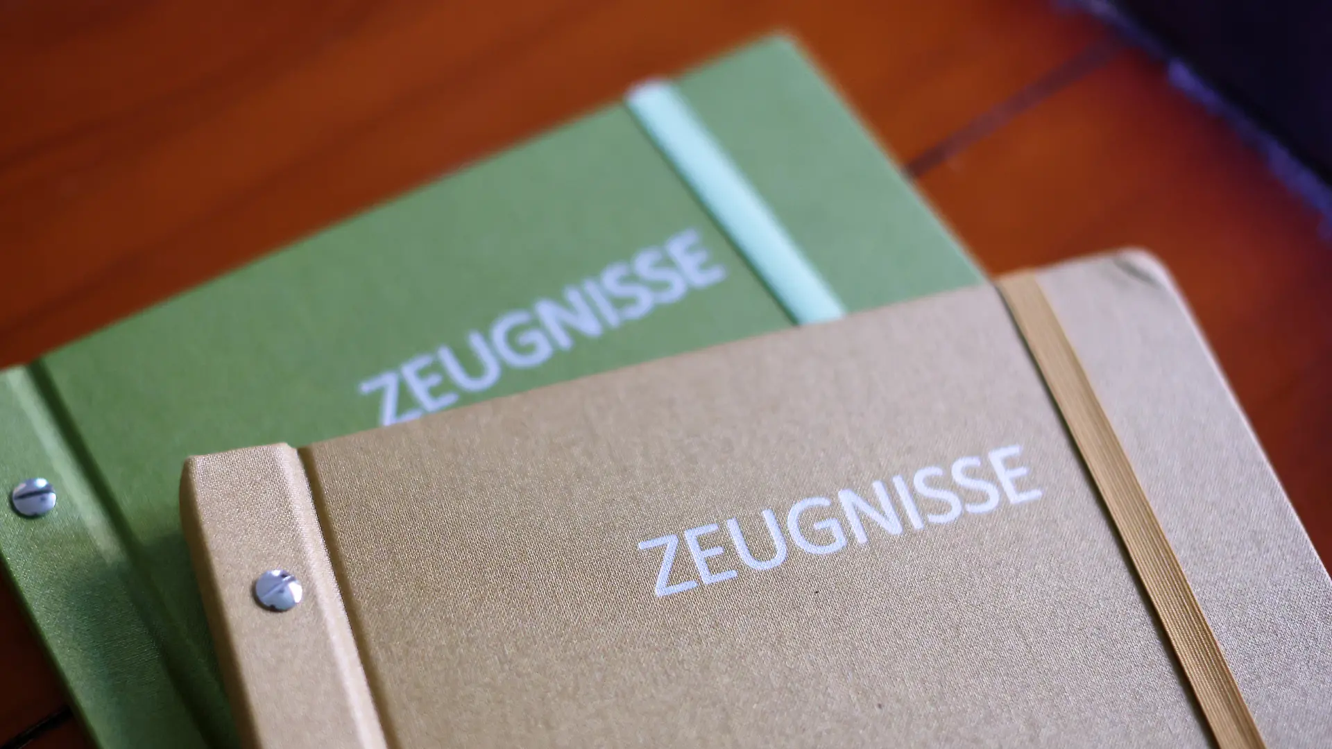 Zwei Zeugnismappen liegen auf einem Tisch.