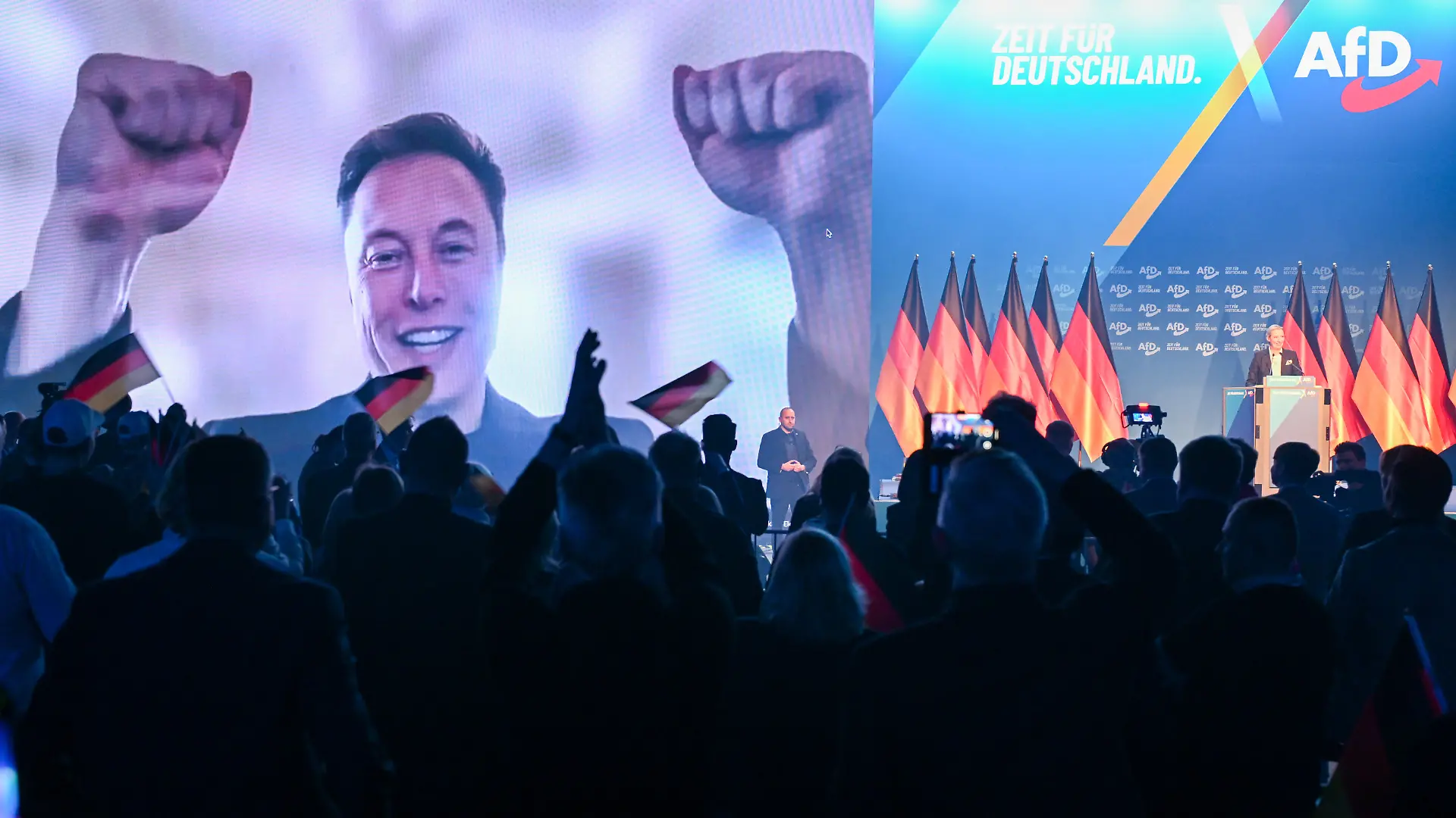 Über eine Videoeinblendung unterhält sich US-Miliardär Elon Musk mit Alice Weidel (r), Bundesvorsitzende der AfD, beim Wahlkampfauftakt der AfD. Am 23.02.2025 sind rund 59 Millionen Bundesbürger aufgerufen, einen neuen Bundestag zu wählen. (zu dpa: «Brandenburger kritisieren Elon Musk für AfD-Wahlkampfhilfe») +++ dpa-Bildfunk +++