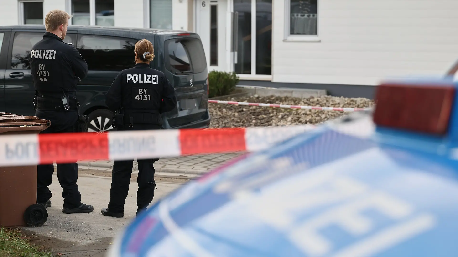 09.10.2026, Bayern, Berngau: Polizisten stehen an einer Flatterbandabsperrung vor einem Tatort. Ein 60-jähriger Mann soll bei einer routinemäßigen Waffenkontrolle eine Mitarbeiterin und einen Mitarbeiter des Landratsamts Neumarkt in der Oberpfalz erschossen haben. (zu dpa: «Schütze von Berngau bei Festnahme schwer verletzt») Foto: Daniel Löb/dpa +++ dpa-Bildfunk +++