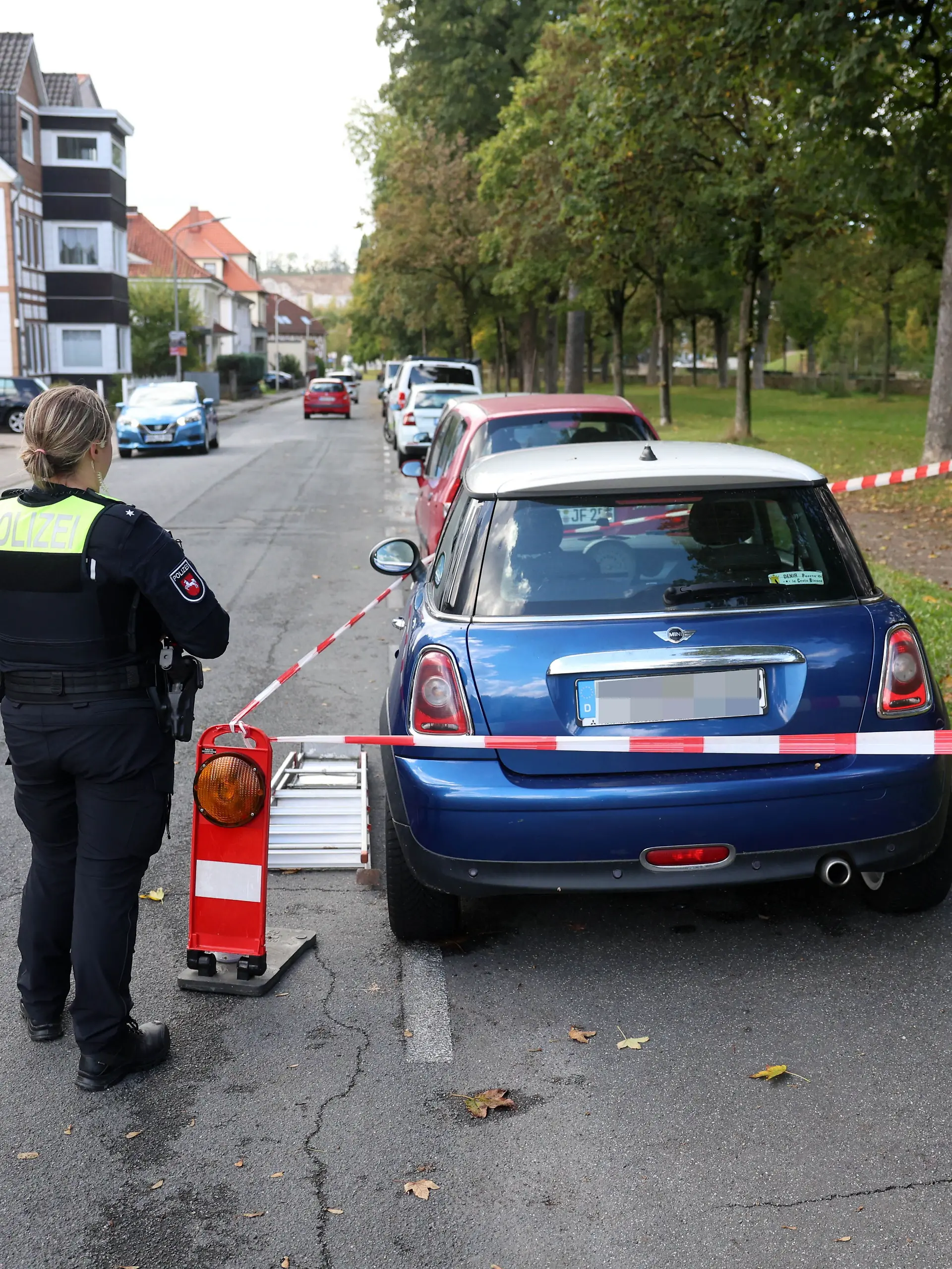 Rätsel um den blauen Mini! Eine Polizistin sichert das mit Absperrband umgebene Auto in Osterode. Ganz in der Nähe wurde ein 37-Jähriger tot gefunden.