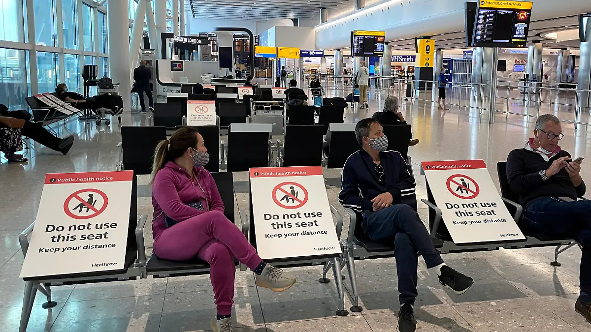 People sit amongst socially-distanced seating signs at Heathrow Airport, as the spread of the coronavirus disease (COVID-19) continues, in London, Britain, May 10, 2020.  REUTERS/Toby Melville