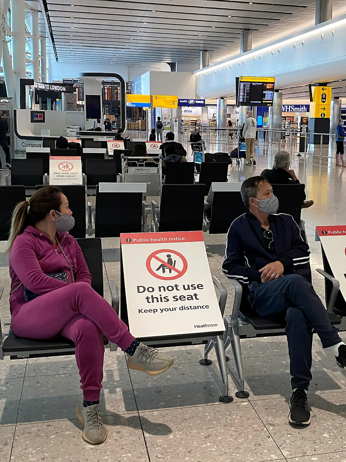 People sit amongst socially-distanced seating signs at Heathrow Airport, as the spread of the coronavirus disease (COVID-19) continues, in London, Britain, May 10, 2020.  REUTERS/Toby Melville