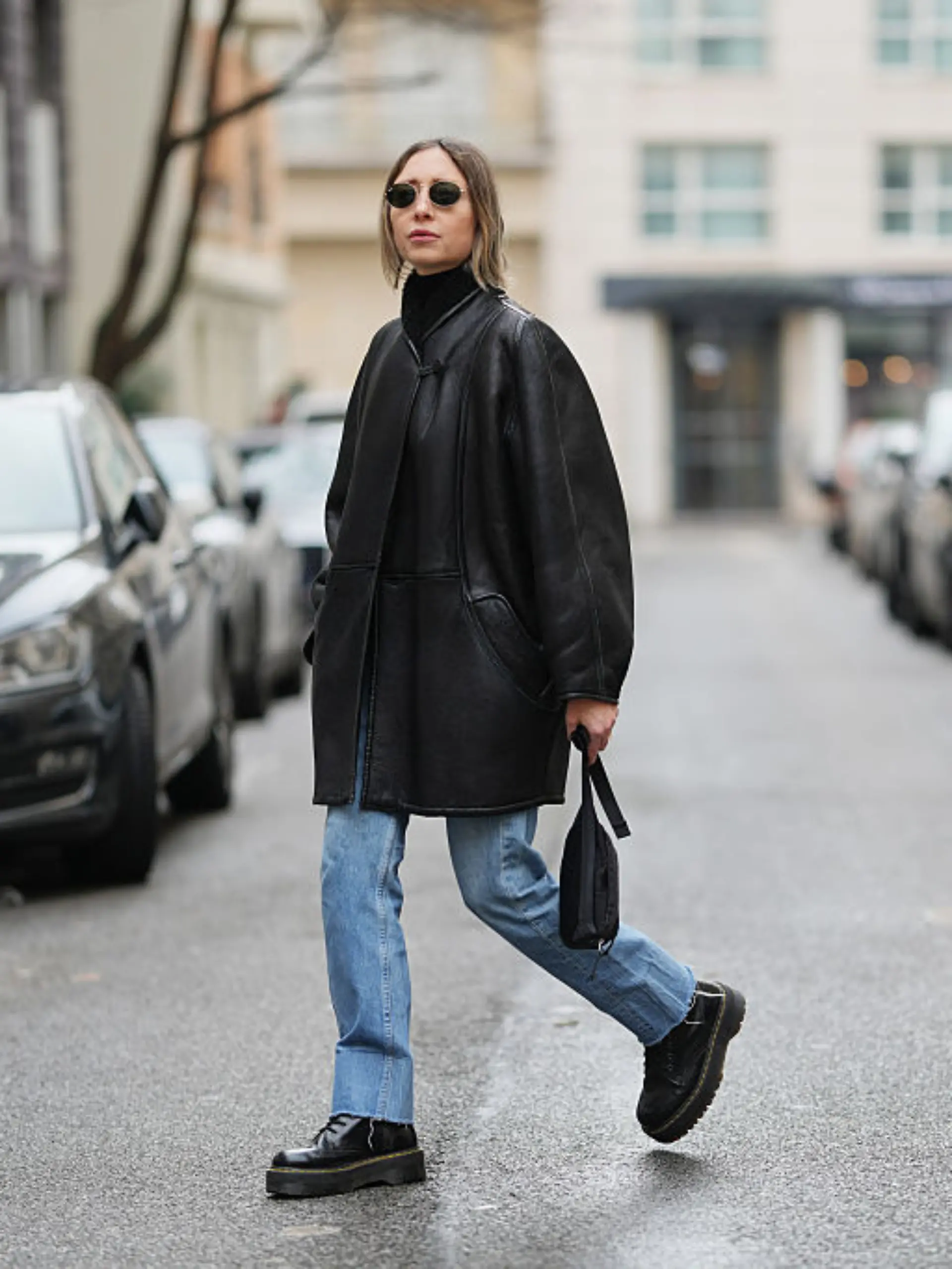 Emy Venturini kombiniert Dr. Martens zu einem schwarzen Mantel, Sonnenbrille und Straight-Leg-Jeans. 