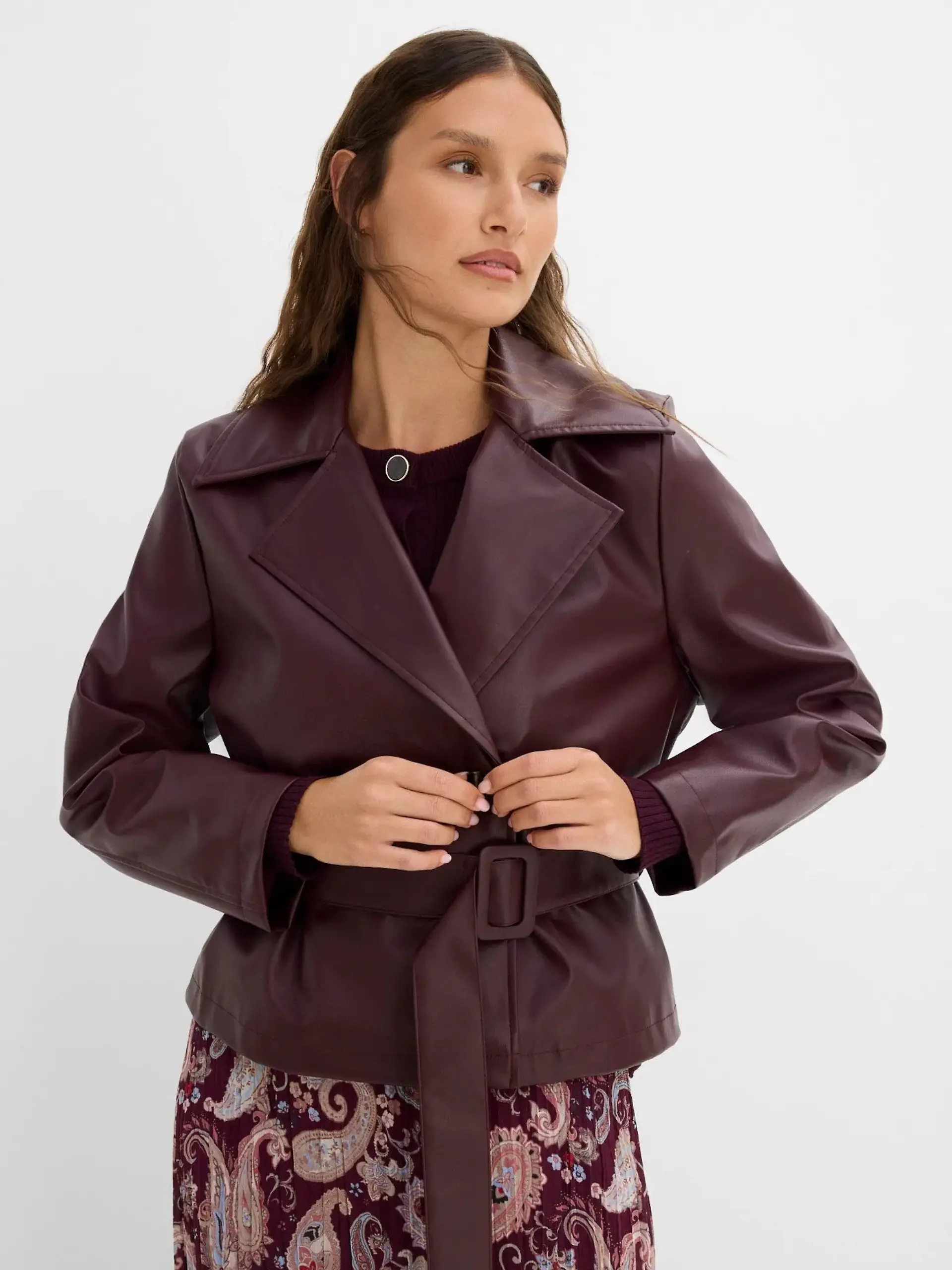 Ein Model trägt eine dunkelrote Trenchjacke von Bonprix.