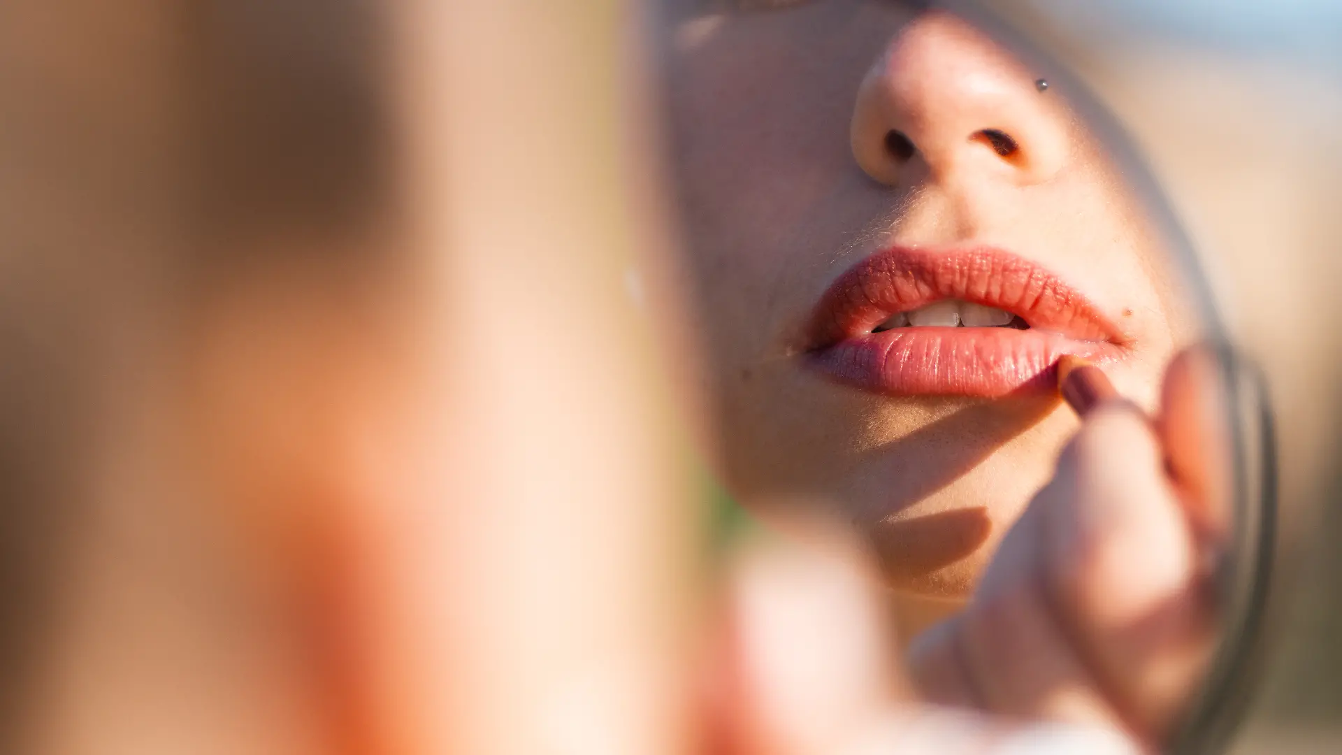 Nahaufnahme: Frau malt ihre Lippen mit Lippenstift an.