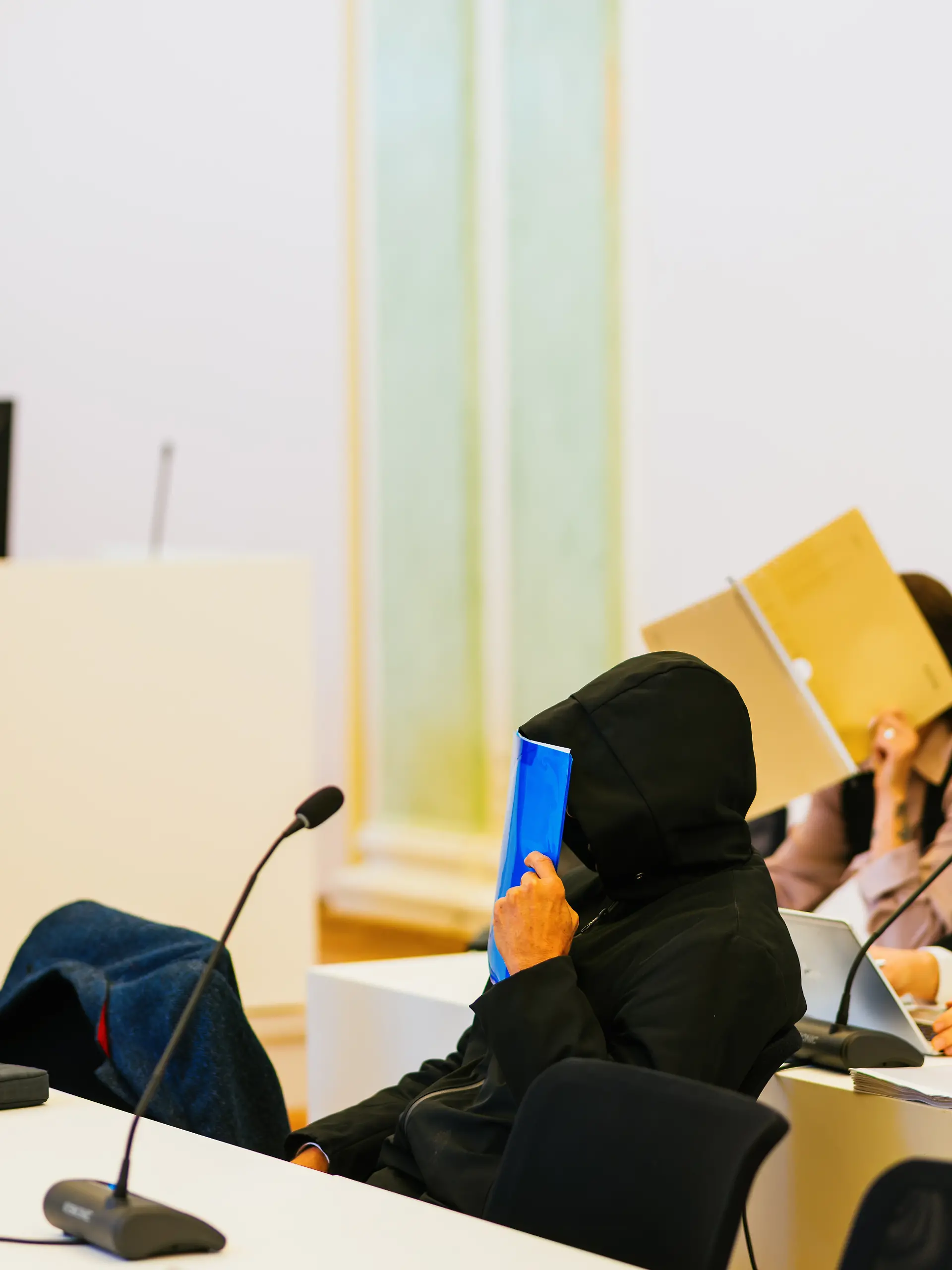 Zwei Angeklagte sitzen zwischen ihren Verteidigern Nico Schmid (r) und Jan-Georg Wennekers (l). Einem angeklagten Ehepaar werden neben 50 Fällen von Diebstahl, beziehungsweise wegen Beihilfe, mindestens 250 Fälle vorgeworfen. Der Ehemann war nach Angaben des Gerichts bis Ende Oktober 2024 als Bestatter beim Eigenbetrieb Friedhöfe der Stadt Freiburg angestellt. Ihm wird vorgeworfen, von 2013 an Zahngold von Leichen entwendet zu haben, die verbrannt werden sollten - teilweise mit grober Gewalt. Außerdem soll er den Leichen Schmuck, Uhren und sonstige Wertgegenstände abgenommen haben. Seine Frau soll ihn bei den Taten unterstützt haben. (zu dpa: «Zahngold von Toten geklaut? Bestatter droht Haftstrafe») +++ dpa-Bildfunk +++
